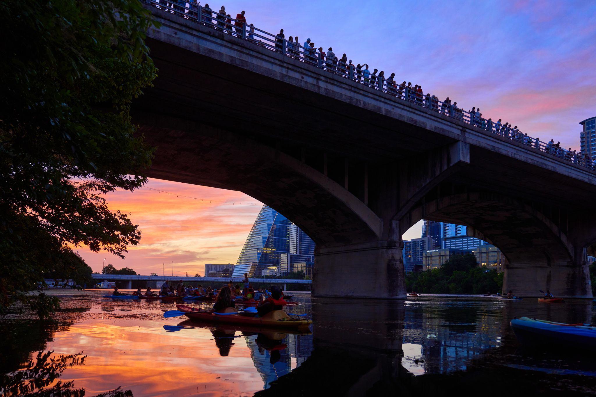 Kayakers on the water at sunset beneath the Congress Avenue bridge, a crowd lining the bridge — Adventure & outdoor photography, Austin Adventure & Outdoor