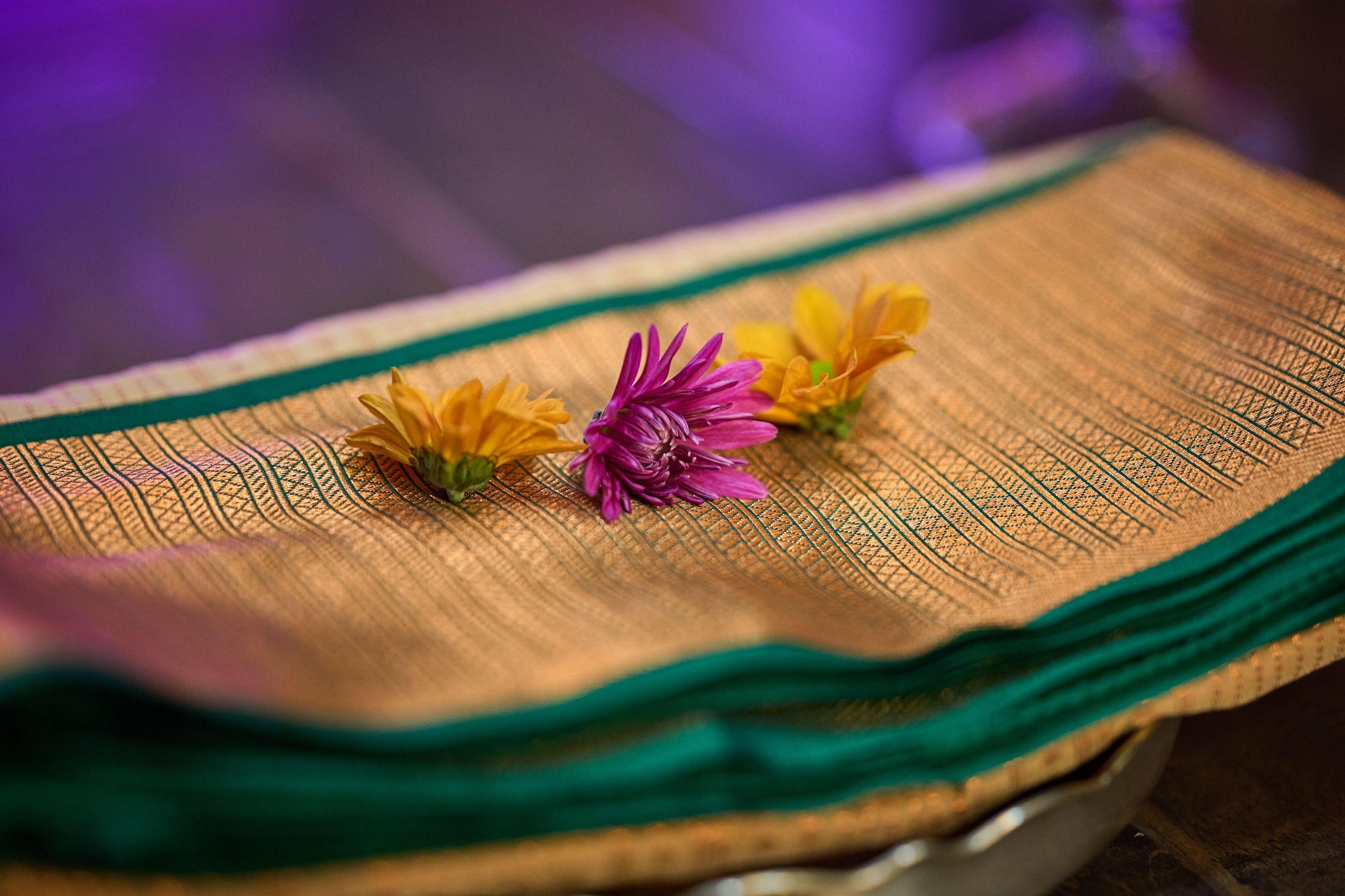 Close view of fresh flowers resting on a folded gold and green silk sari — Religious Ceremonies photography, Austin A close view of fresh flowers resting on a folded gold and green silk sari.