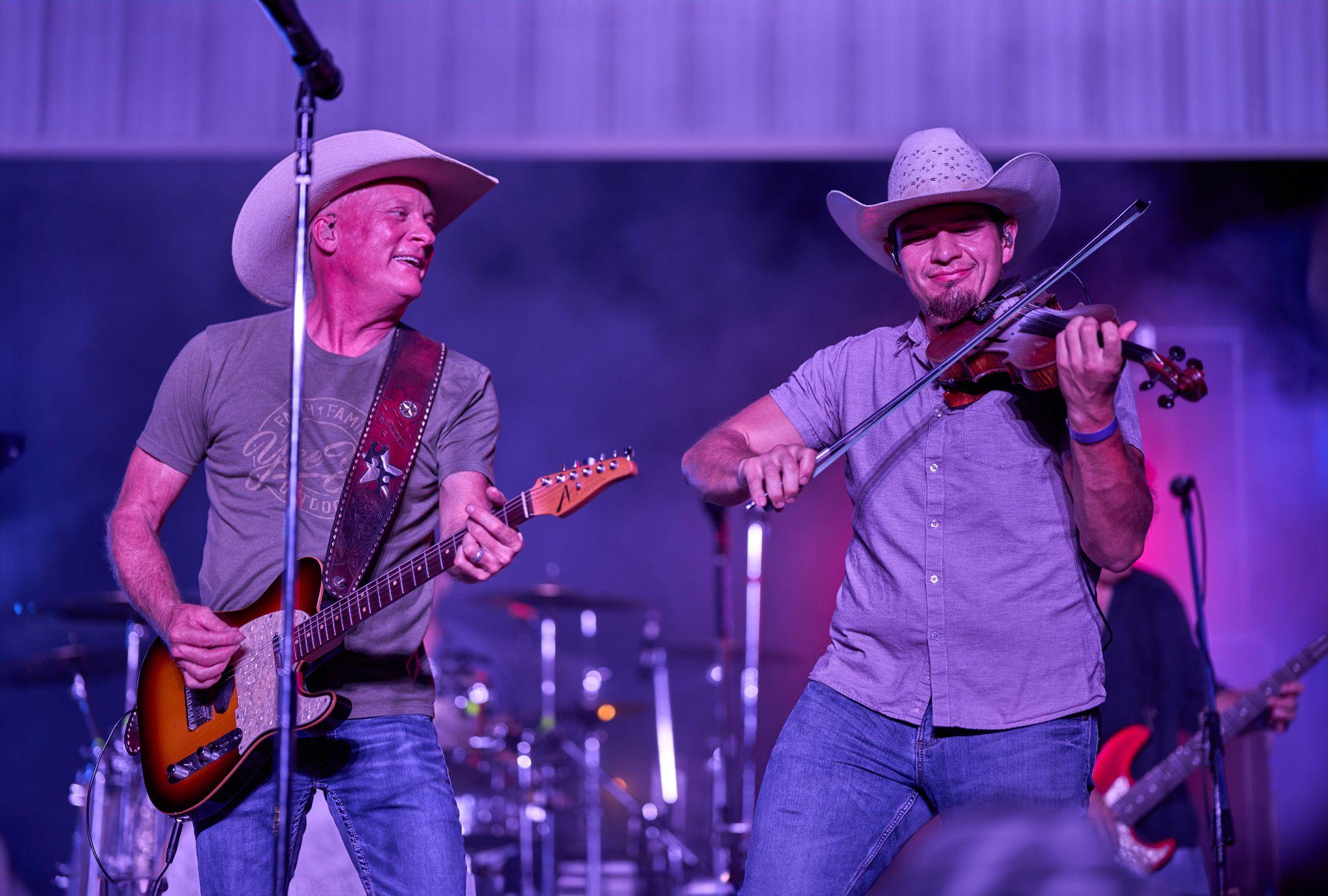 Two musicians in cowboy hats playing guitar side by side on stage — Live music photography, Austin Two musicians in cowboy hats playing guitar side by side on stage.