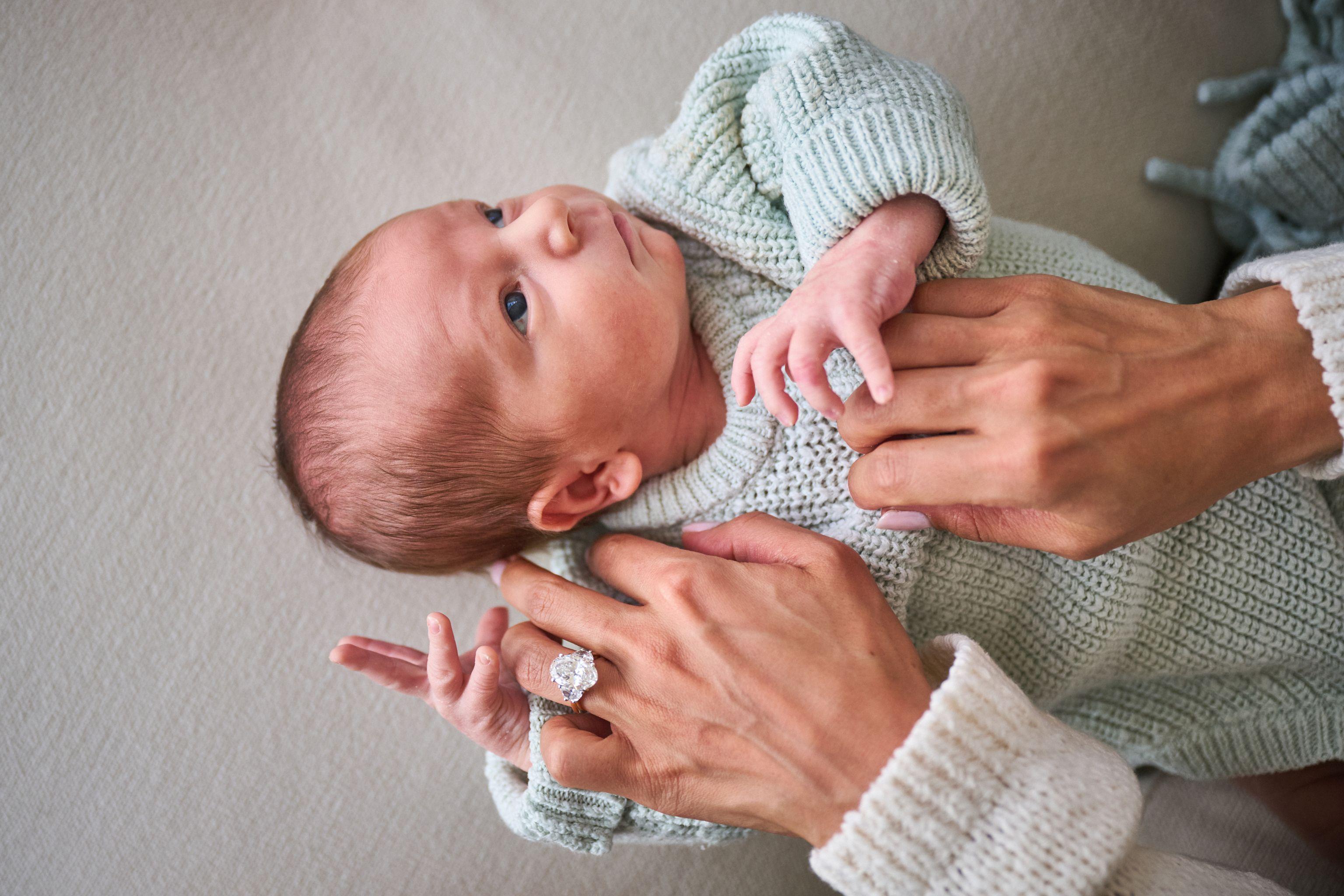 Newborn in a knitted green romper held in his mother's hands — Newborn photography, Austin A newborn in a knitted green romper held in his mother's hands.