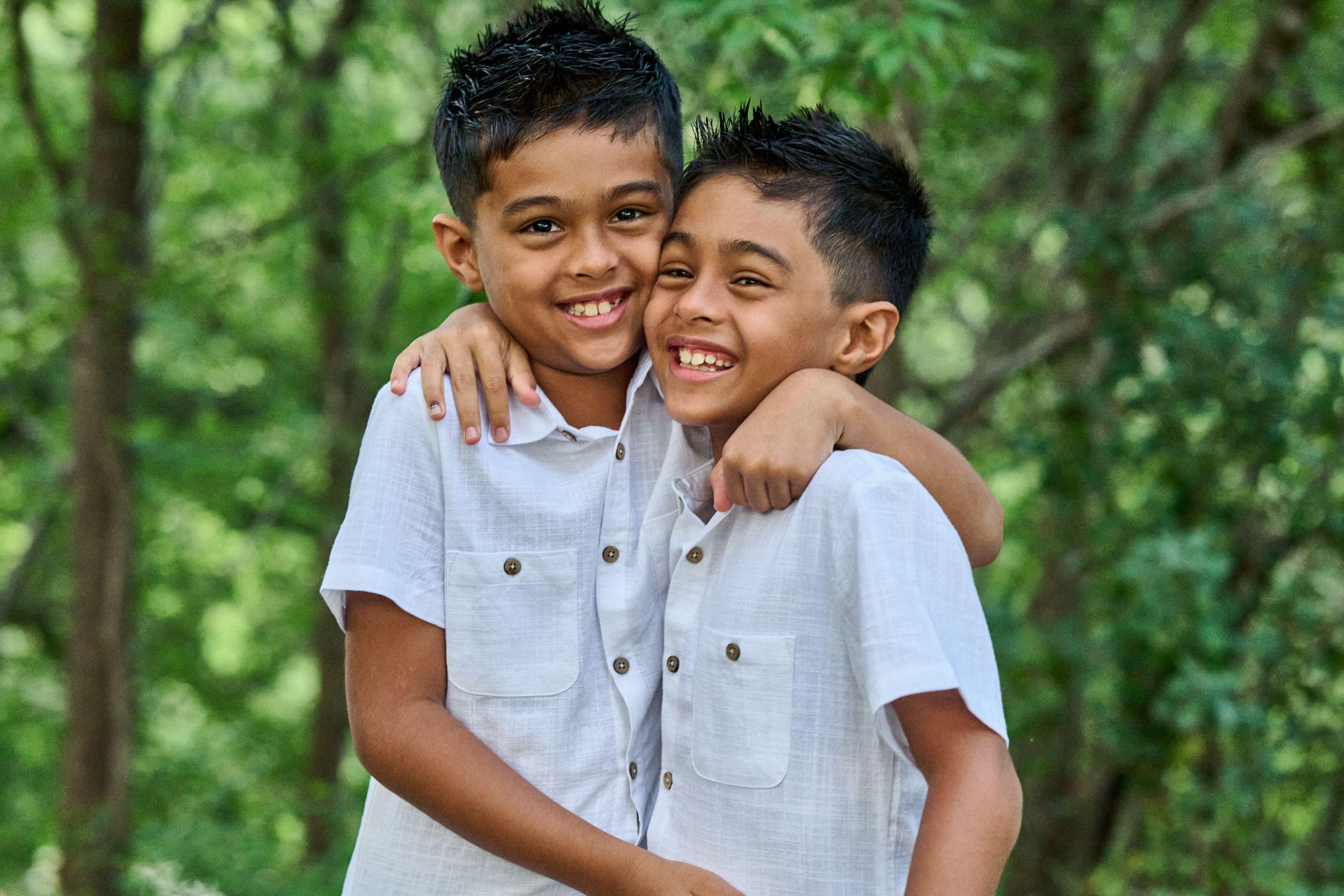 Two brothers in white shirts with their arms around each other, laughing — Kids Portraits photography, Austin Two brothers in white shirts with their arms around each other, laughing.