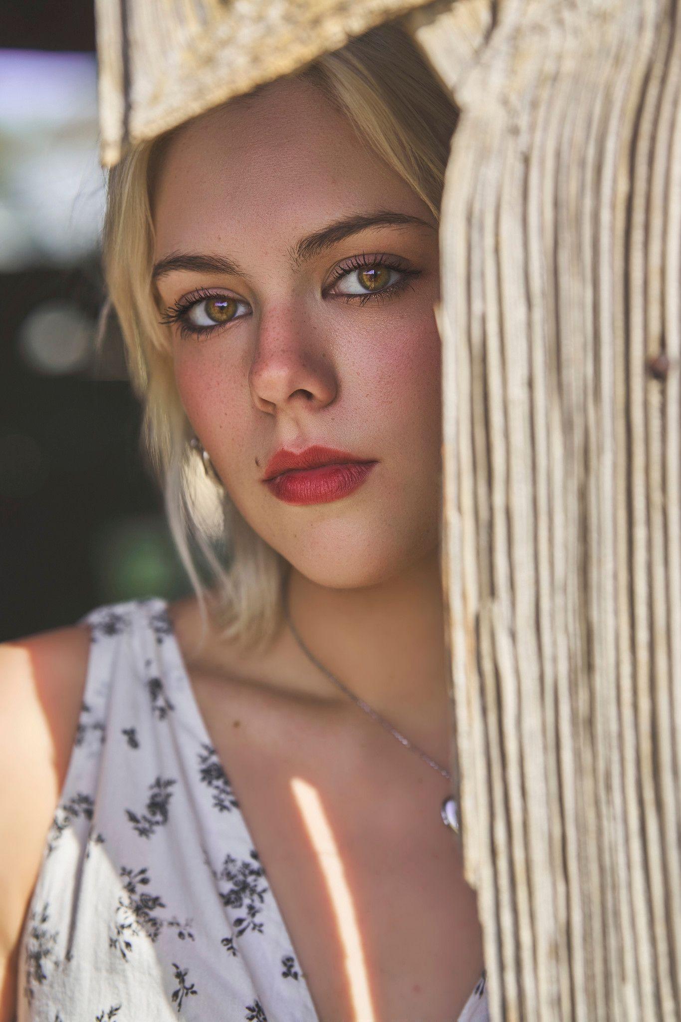 Close portrait of a woman with dappled light across her face, beside a wooden post — Photo retouching, Austin A close portrait of a woman with dappled light across her face, beside a wooden post.