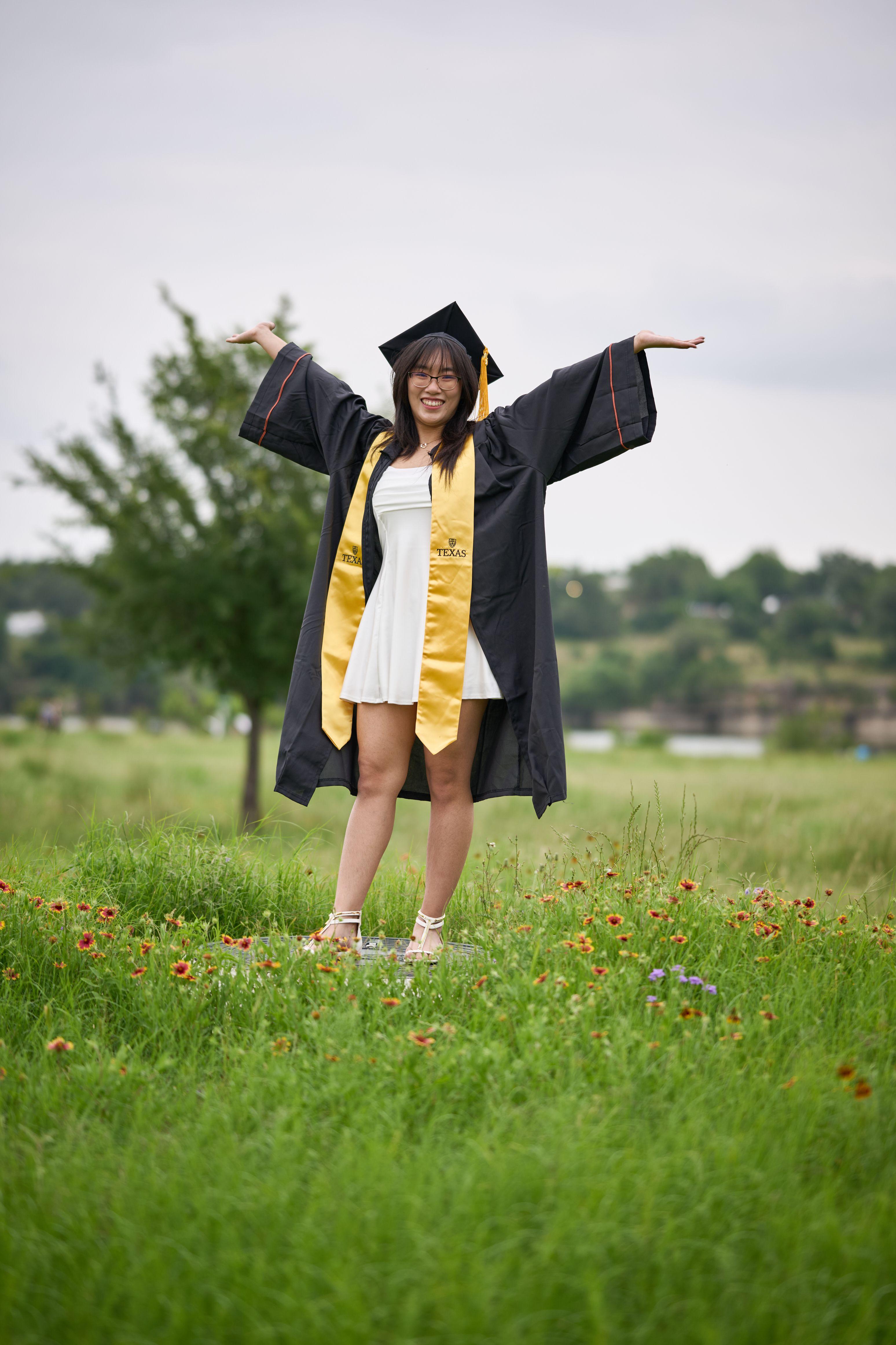 Graduate in cap and gown with her arms flung wide in the wildflower meadow — Brushy Creek Lake Park photography, Austin A graduate in cap and gown with her arms flung wide in the wildflower meadow at Brushy Creek Lake Park