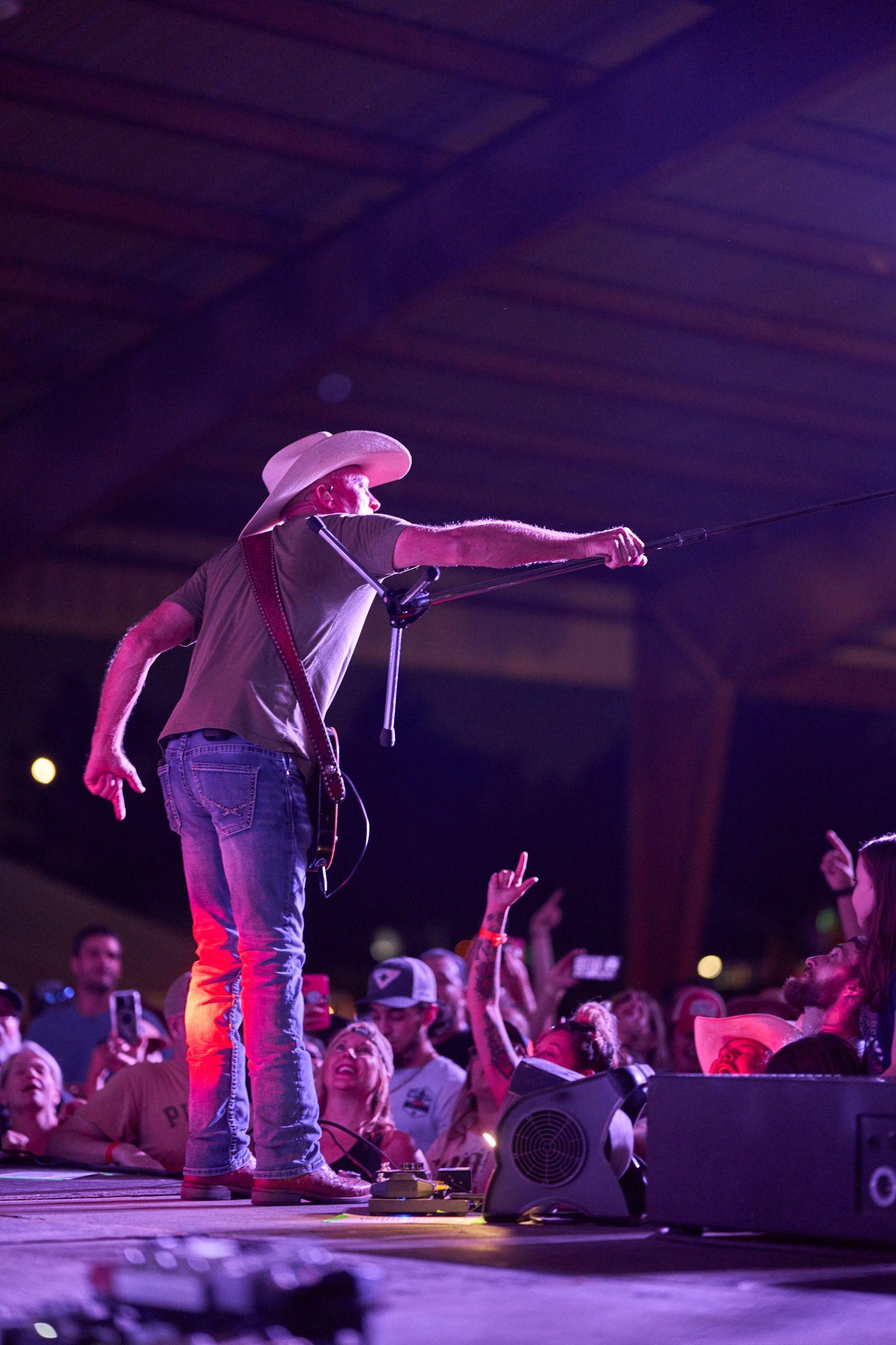 Performer in a cowboy hat reaching out to the crowd from a festival stage — Festival photography, Austin A performer in a cowboy hat reaching out to the crowd from a festival stage.