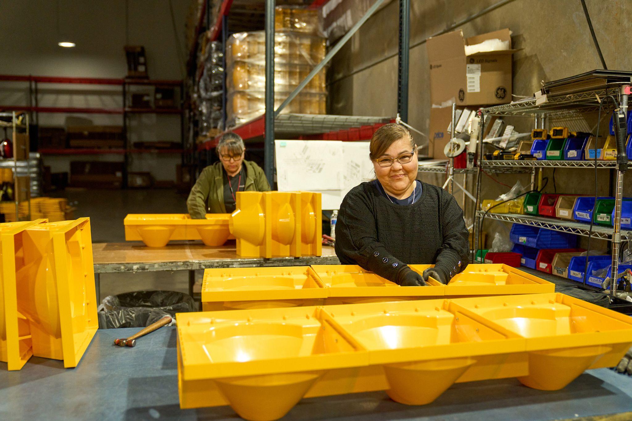 Two workers behind a row of yellow molded plastic containers in a warehouse — Industrial photography, Austin Two workers behind a row of yellow molded plastic containers in a warehouse