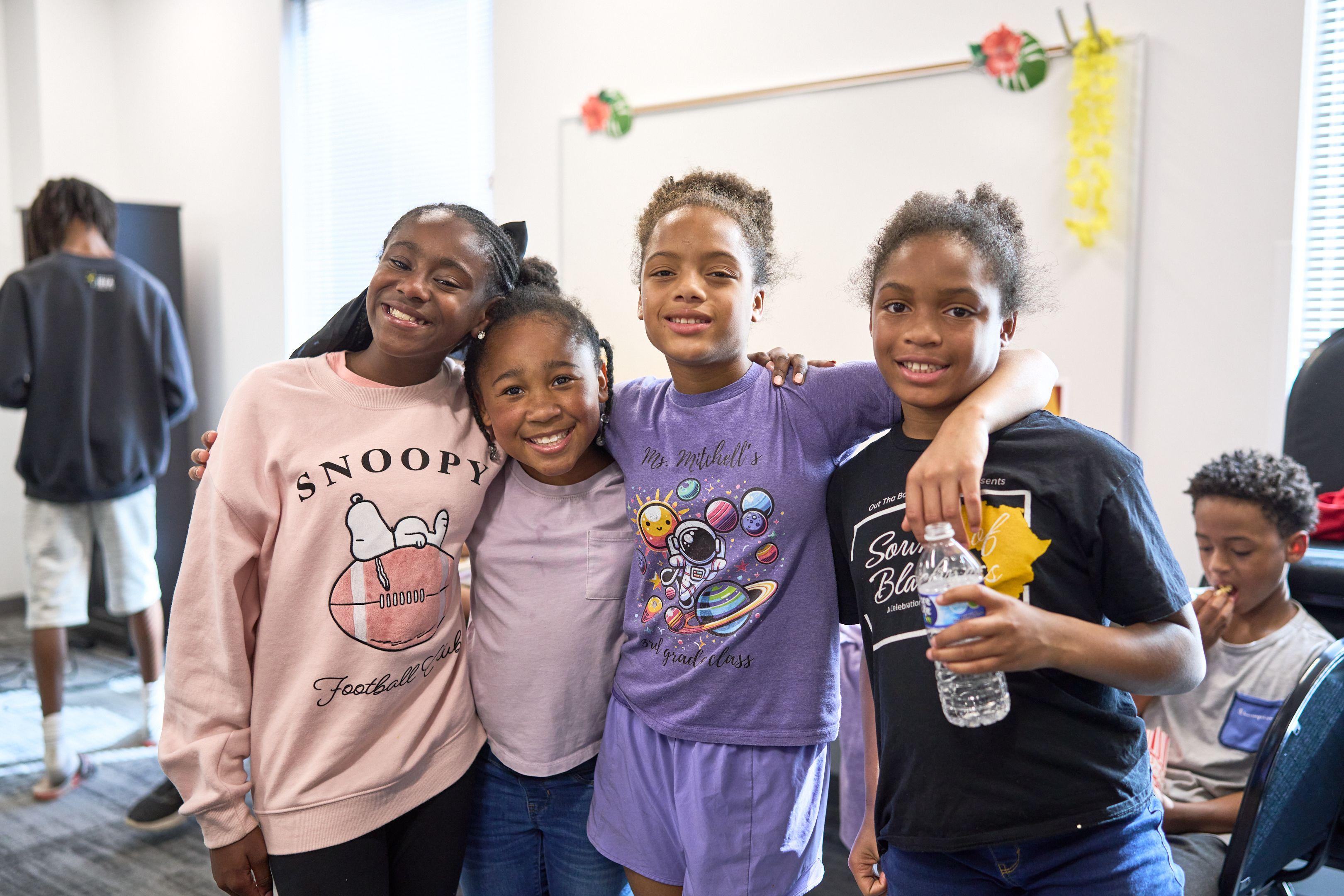 Four students standing arm in arm outside, smiling at the camera — School event photography, Austin School Activities