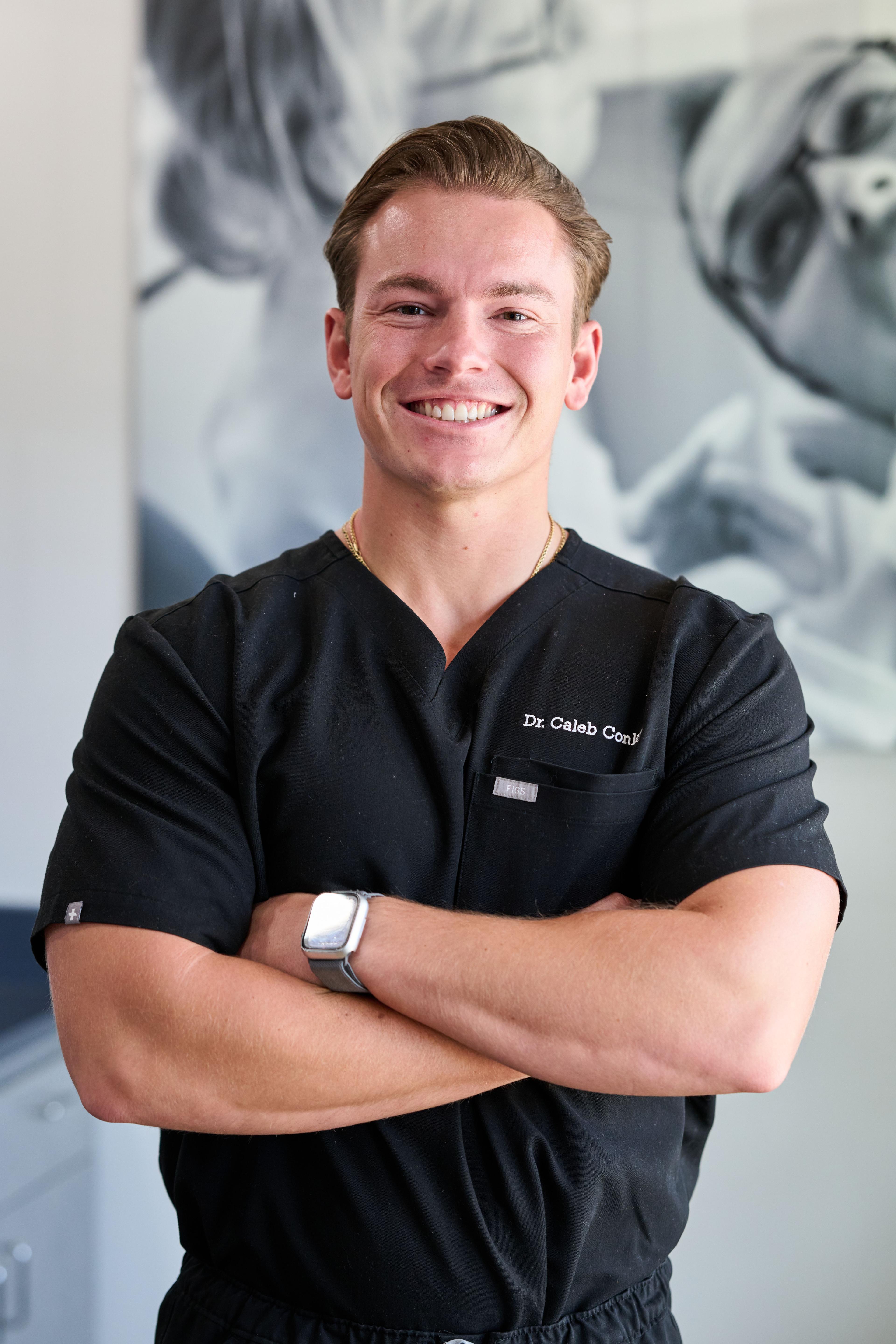 Dentist in black scrubs standing with arms crossed in his practice — Headshot photography, Austin A dentist in black scrubs standing with arms crossed in his practice.