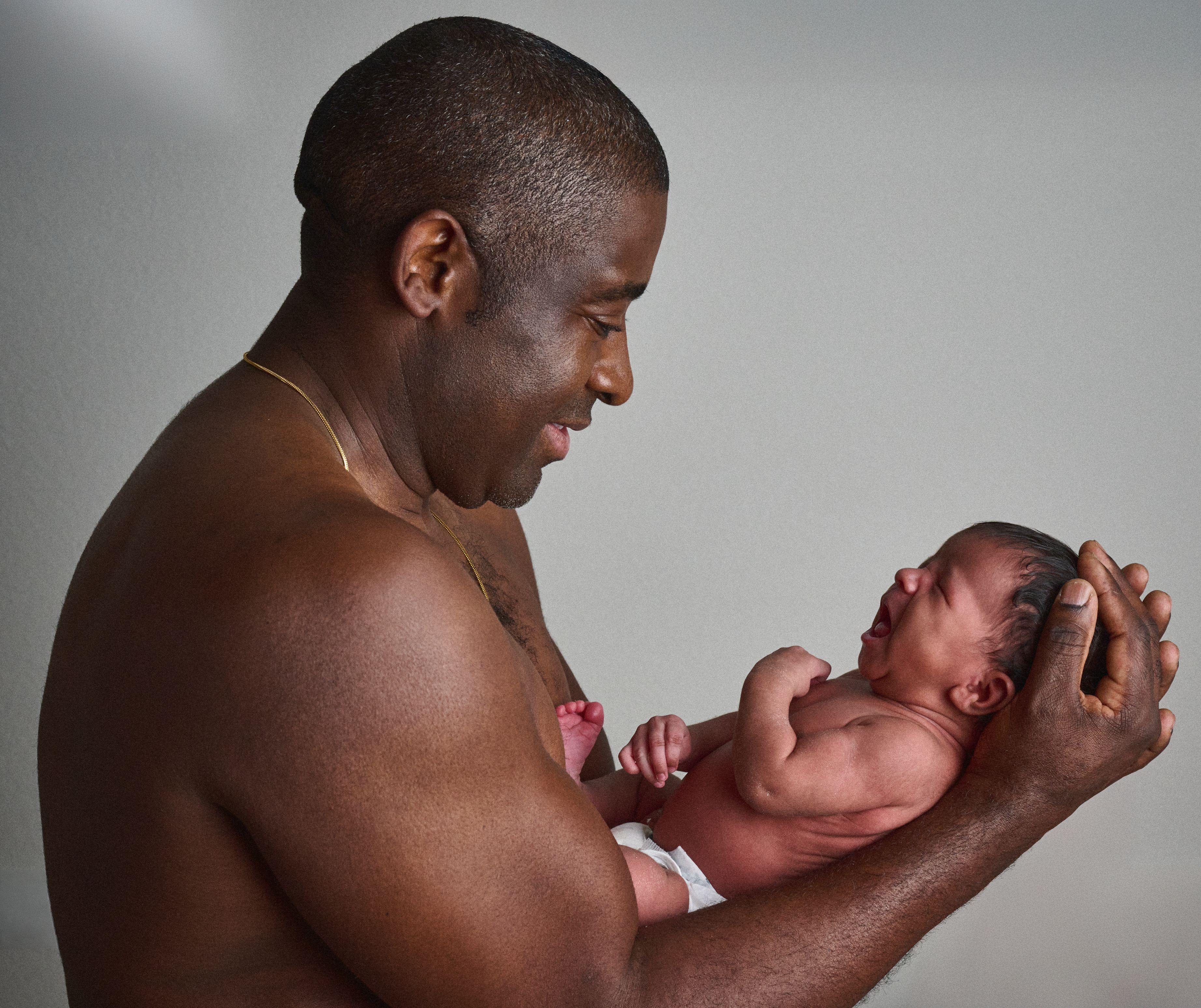 Father in profile holding his newborn out in both hands, looking down at the baby — Mobile photo studio, Austin A father in profile holding his newborn out in both hands, looking down at the baby