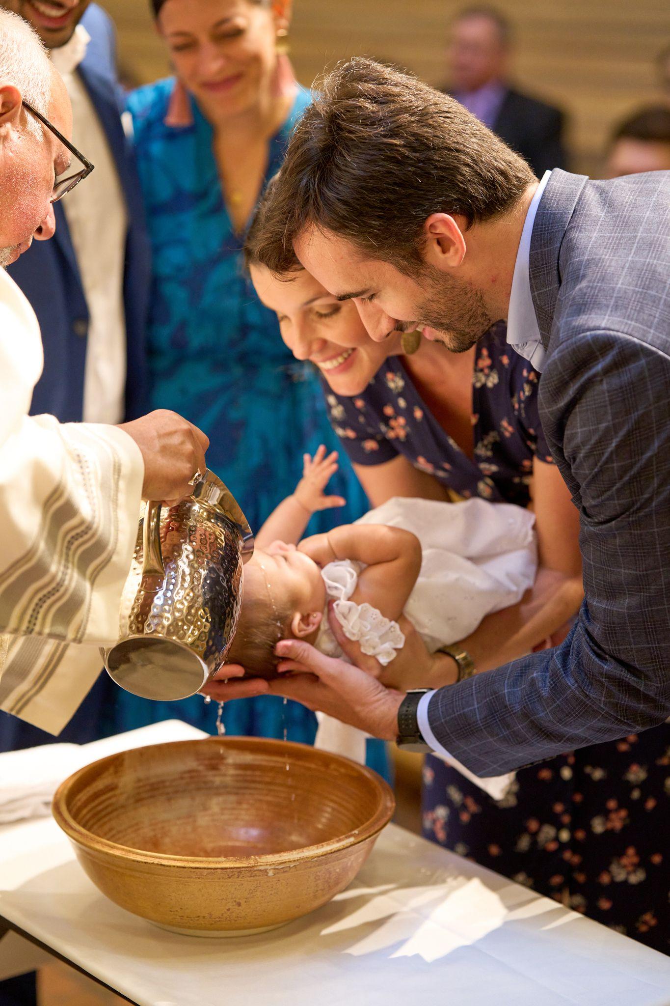 Priest pouring water from a brass ewer over an infant held by parents at the font — Religious Ceremonies photography, Austin A priest pouring water from a brass ewer over an infant held by parents at the font.