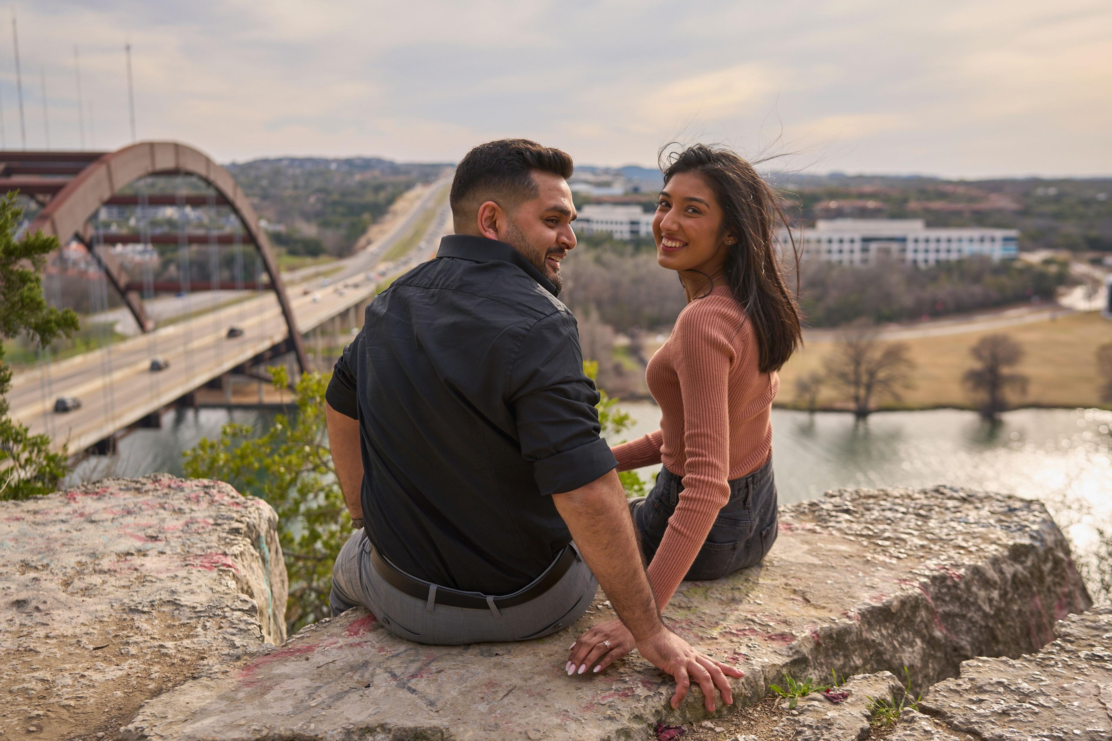 Couple sitting together on a bluff, looking at each other above the river valley — Couples & Anniversary photography, Austin A couple sitting together on a bluff, looking at each other above the river valley.