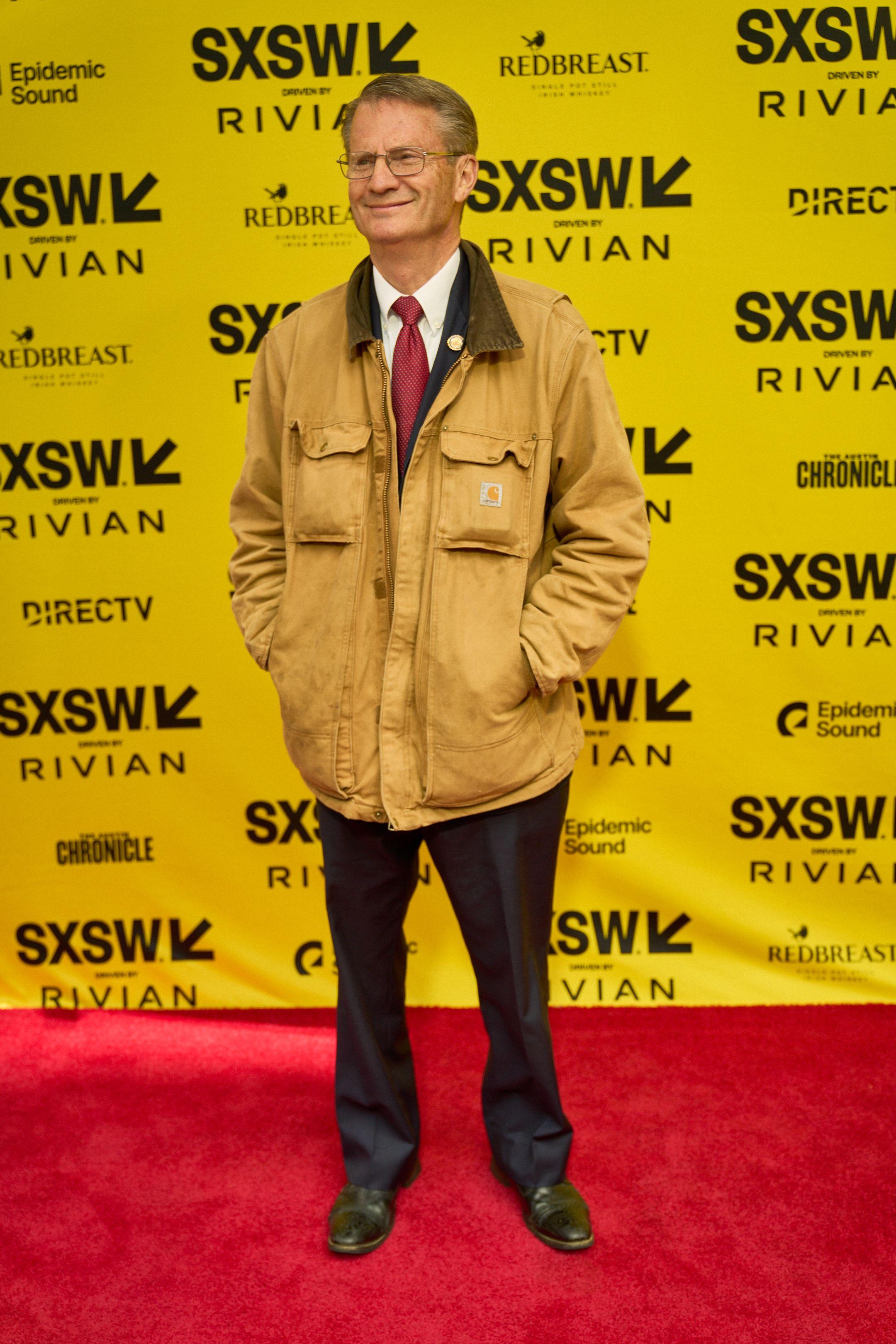 Man in a yellow jacket standing on the red carpet in front of a yellow SXSW backdrop — Production behind-the-scenes, Austin Man in a yellow jacket standing on the red carpet in front of a yellow SXSW backdrop