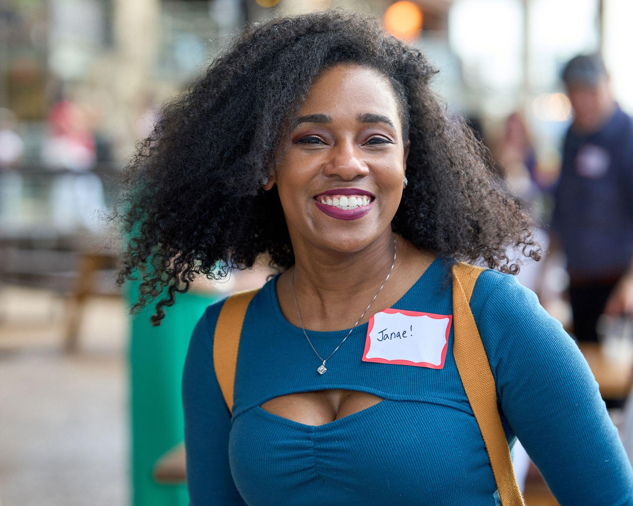 Guest in a teal top with a handwritten name badge smiling straight at camera — Business Parties photography, Austin A guest in a teal top with a handwritten name badge smiling straight at camera.