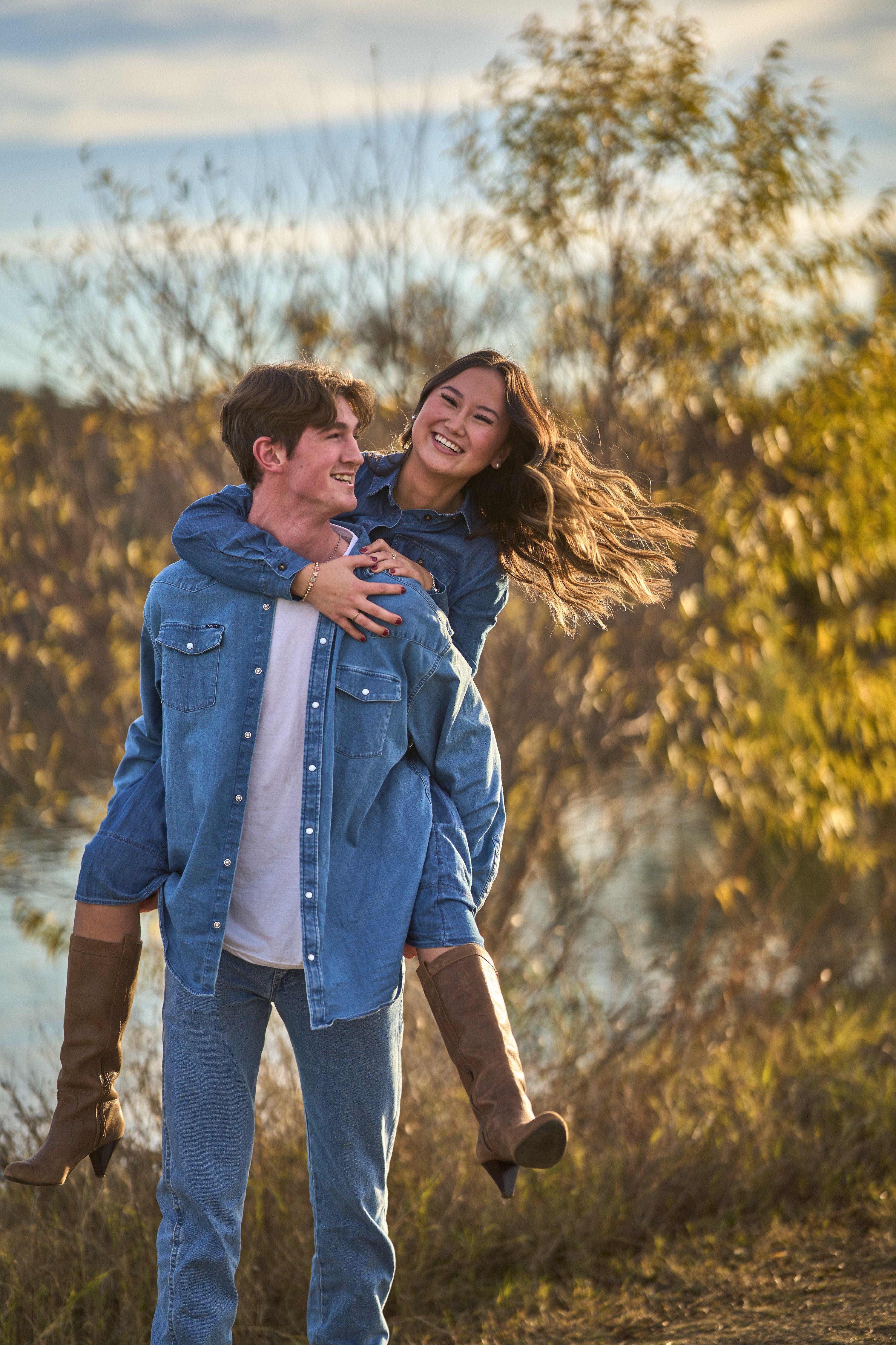 Couple laughing, she jumping onto his back, under yellow autumn foliage — Seasonal Christmas & Fall photography, Austin A couple laughing, she jumping onto his back, under yellow autumn foliage.