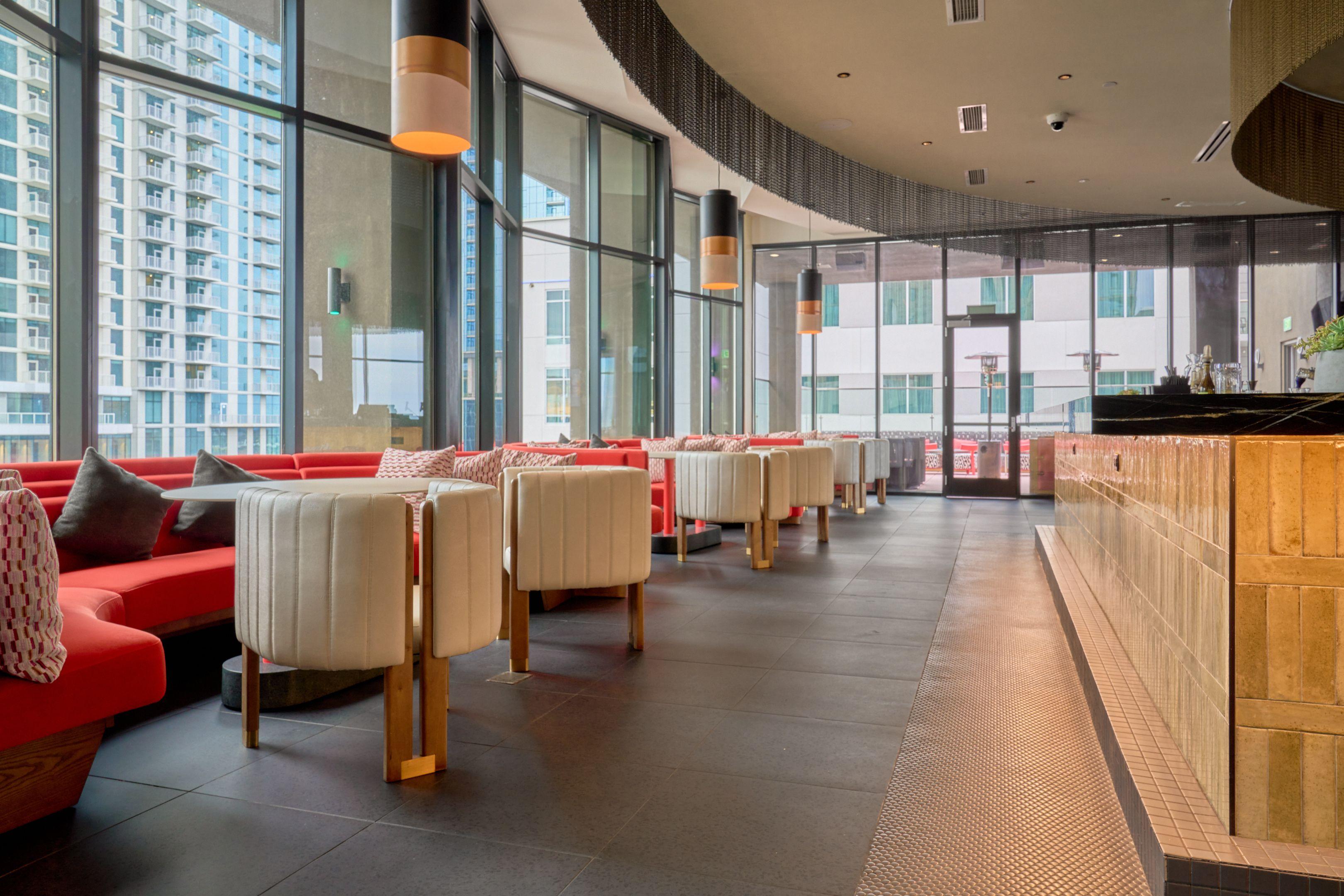 Rooftop restaurant with curved windows, banquettes and city views — Hospitality & leisure photography, Austin A rooftop restaurant with curved windows, banquettes and city views.
