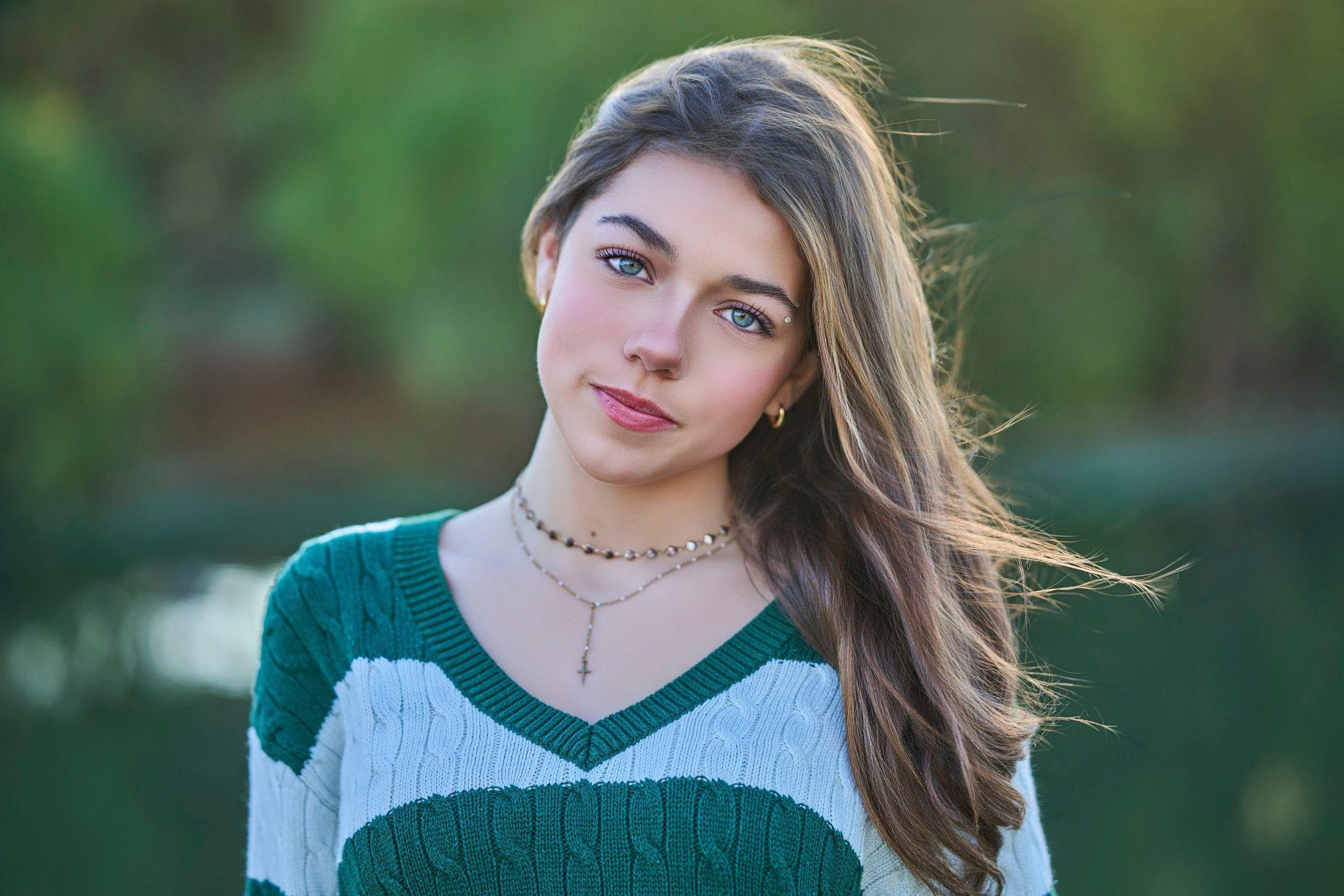 Young woman in a green and white sweater, backlit with flyaway hair against green water — Photo retouching, Austin A young woman in a green and white sweater, backlit with flyaway hair against green water.