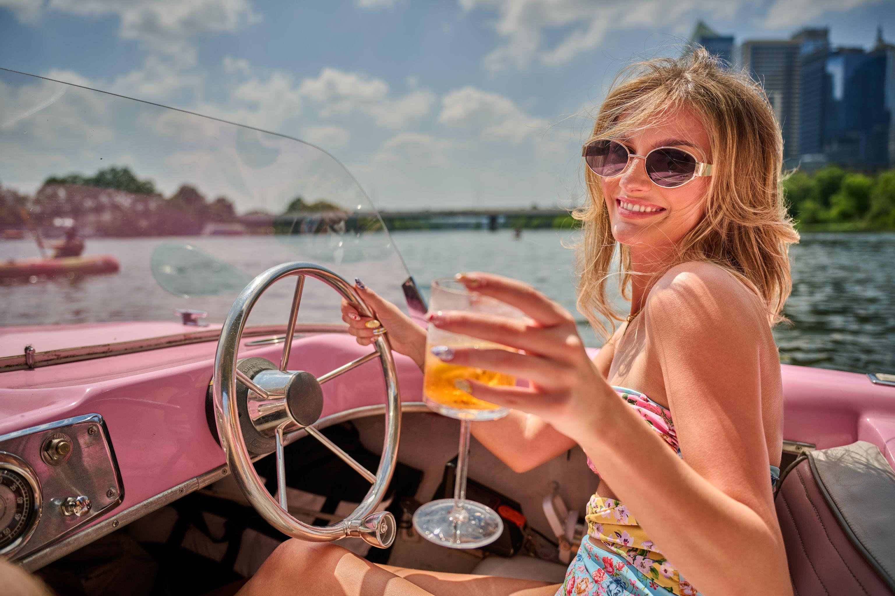 Friends clinking spritz glasses over the wheel of a pink boat on the lake — Bachelor & Bachelorette photography, Austin Friends clinking spritz glasses over the wheel of a pink boat on the lake.