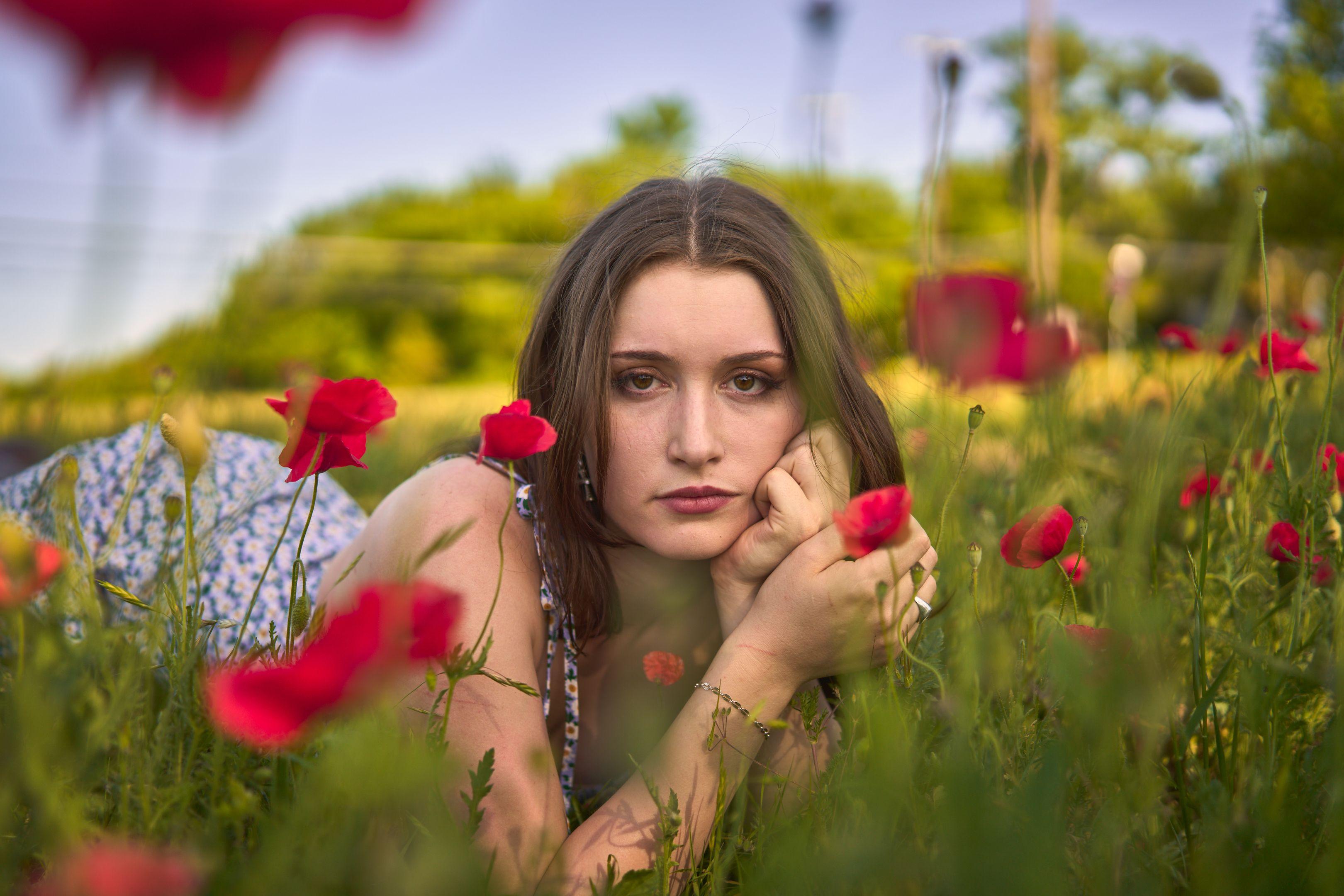 Woman lying in a field of red poppies with her chin resting on her hand — Portrait photography, Austin A woman lying in a field of red poppies with her chin resting on her hand.
