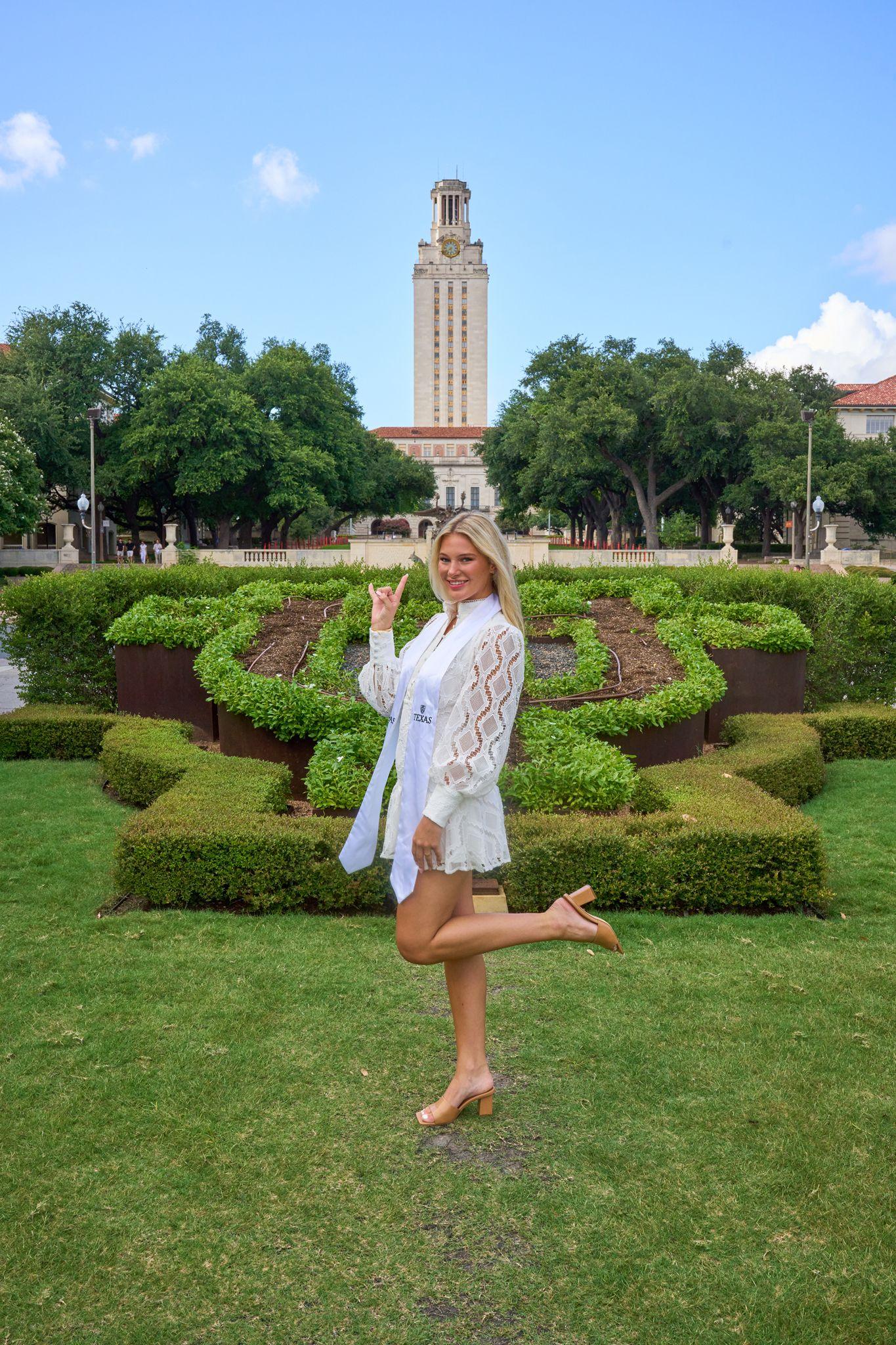 Graduate posing on the hedged lawn with the UT Tower rising — Graduation & Prom photography, Austin A graduate posing on the hedged lawn with the UT Tower rising behind her.