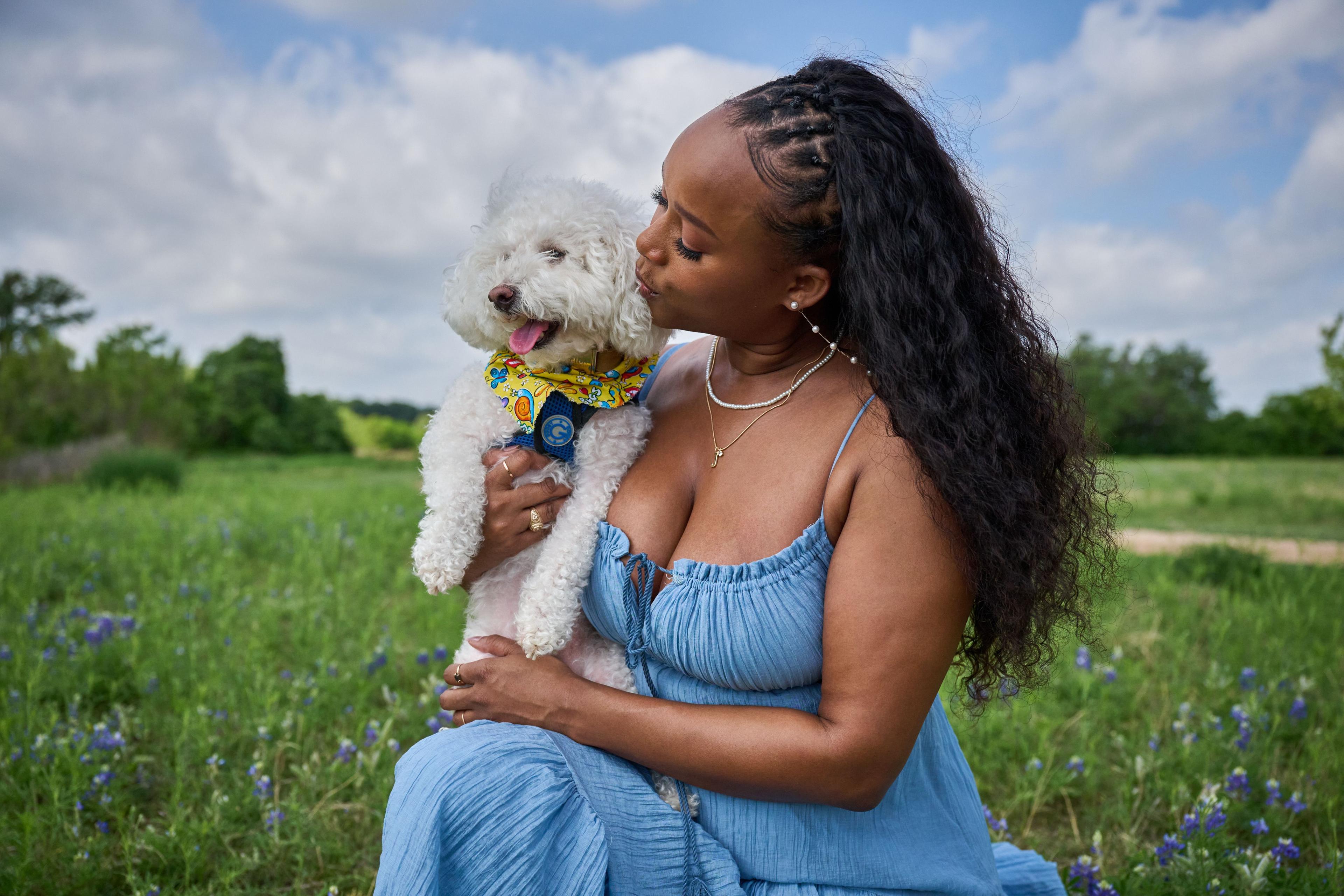 Woman in a blue dress holding and kissing a small white poodle in a meadow — Brushy Creek Lake Park photography, Austin A woman in a blue dress holding and kissing a small white poodle in a meadow.