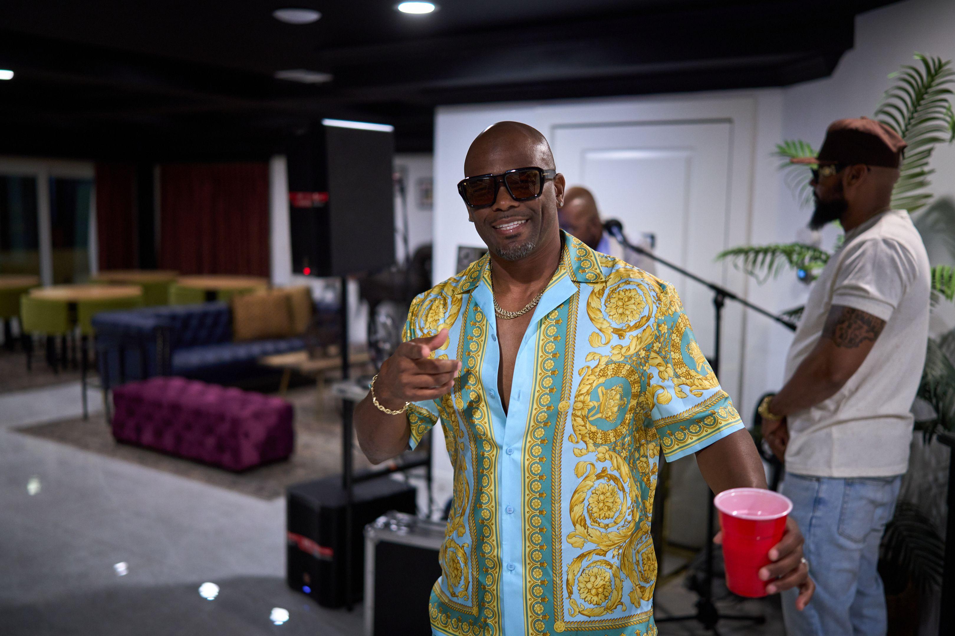 Man in a patterned shirt and sunglasses pointing at the camera at a party — Party & nightlife photography, Austin A man in a patterned shirt and sunglasses pointing at the camera at a party.