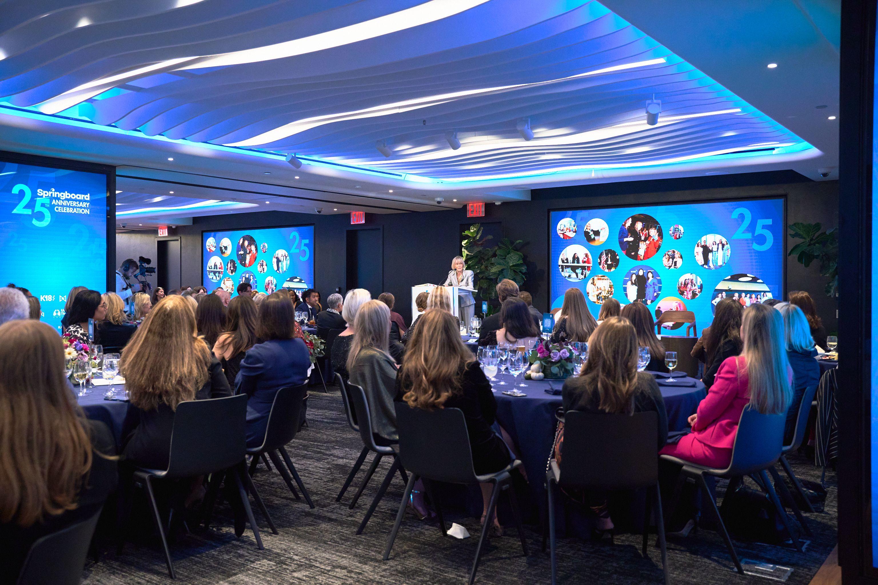 Ballroom of guests seated at round tables under blue ceiling light at an awards dinner — Business Parties photography, Austin A ballroom of guests seated at round tables under blue ceiling light at an awards dinner.