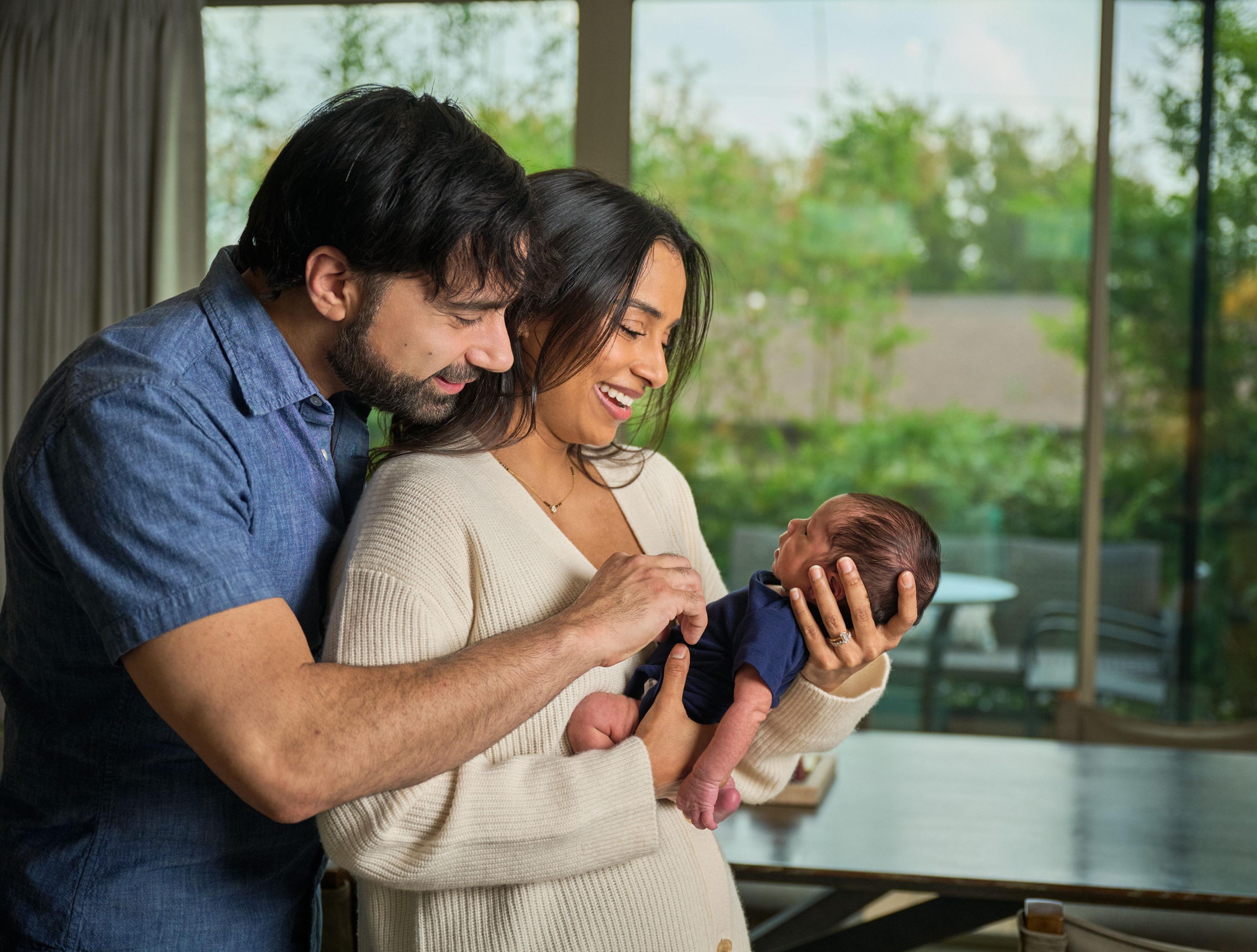 Couple standing together at home holding their newborn between them — Mobile photo studio, Austin A couple standing together at home holding their newborn between them