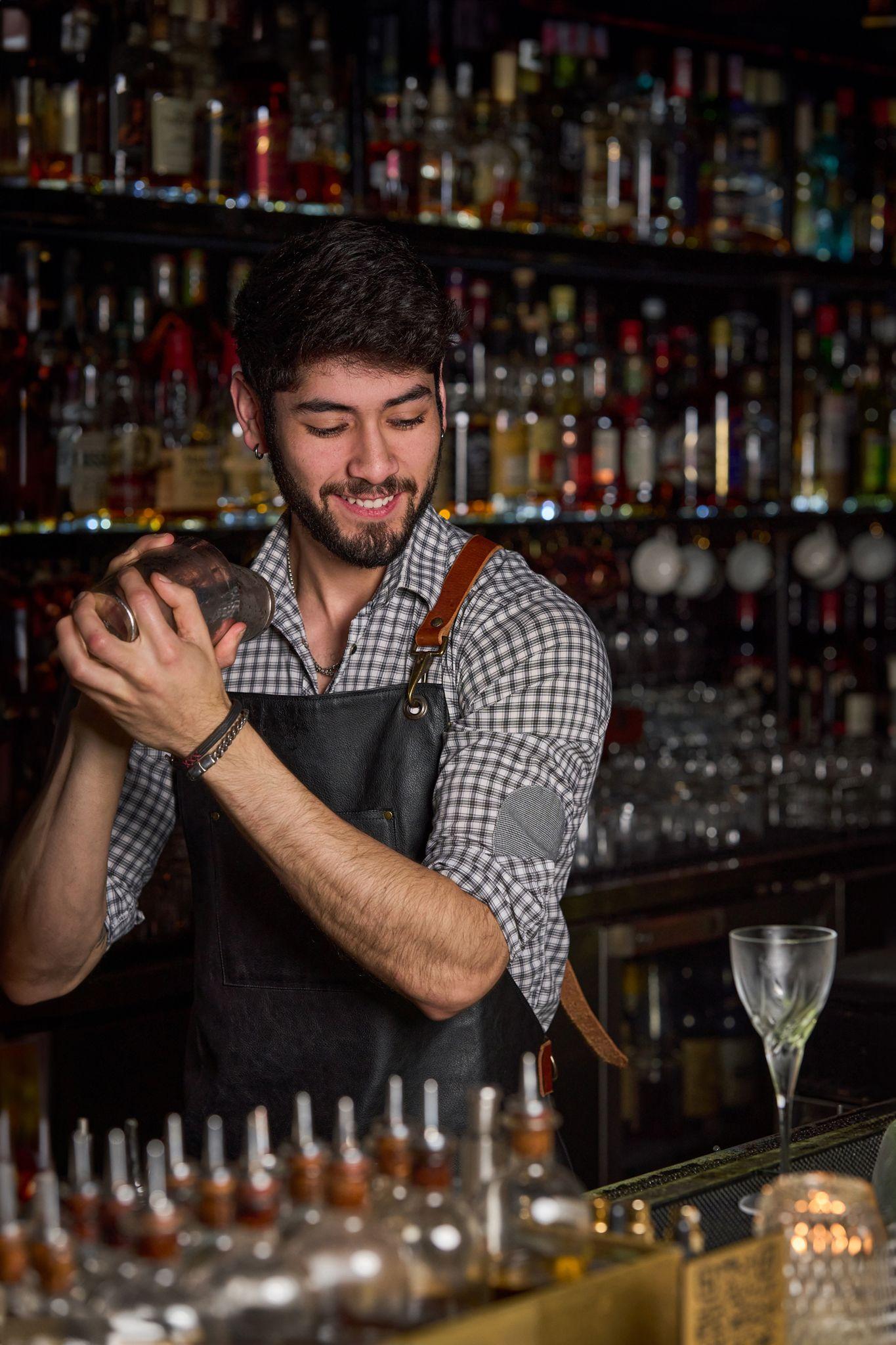 Bartender shaking a cocktail in front of a backlit wall of bottles — Hospitality & leisure photography, Austin A bartender shaking a cocktail in front of a backlit wall of bottles.