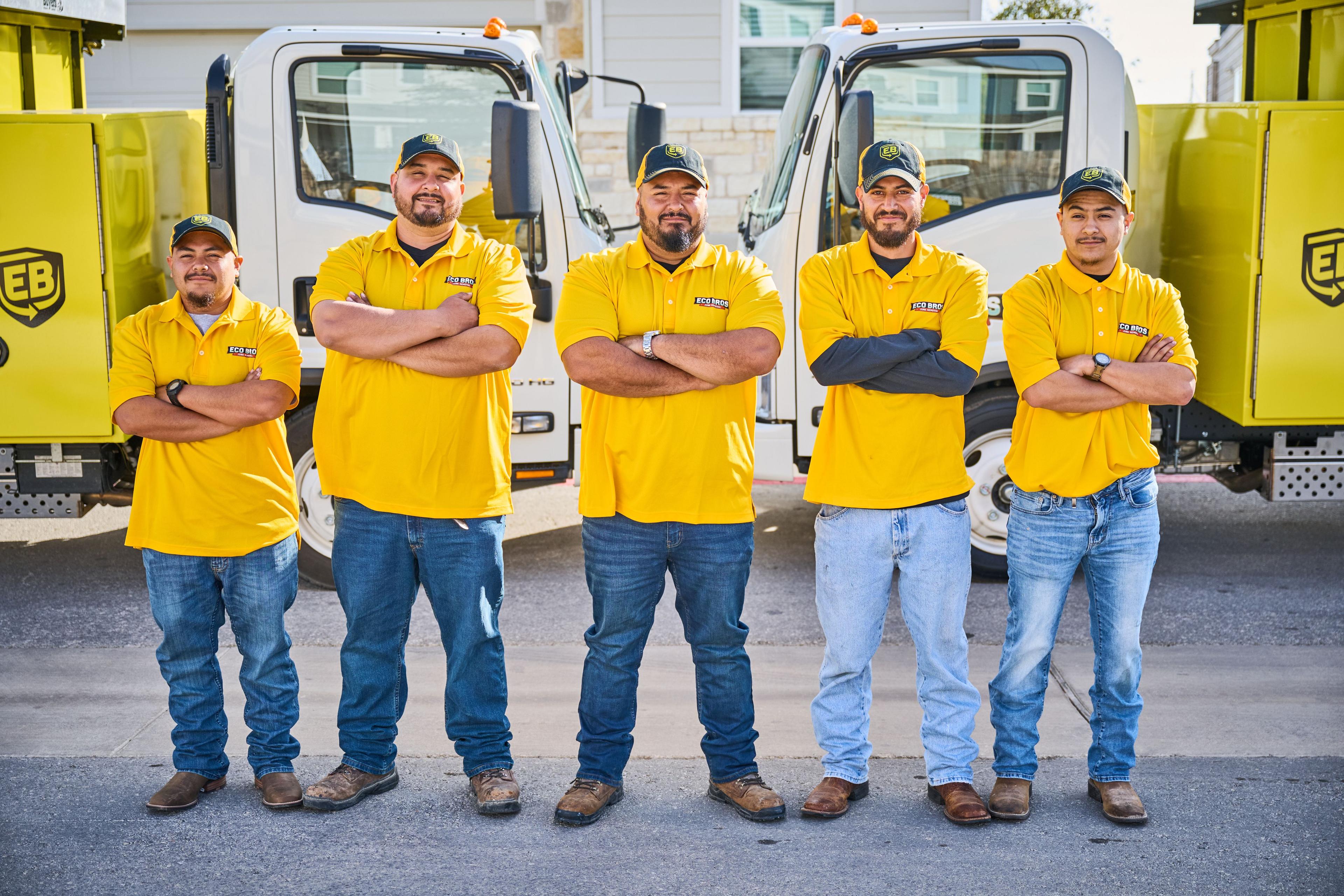 Crew of workers in yellow shirts standing in front of their service trucks — Brand activation photography, Austin A crew of workers in yellow shirts standing in front of their service trucks.