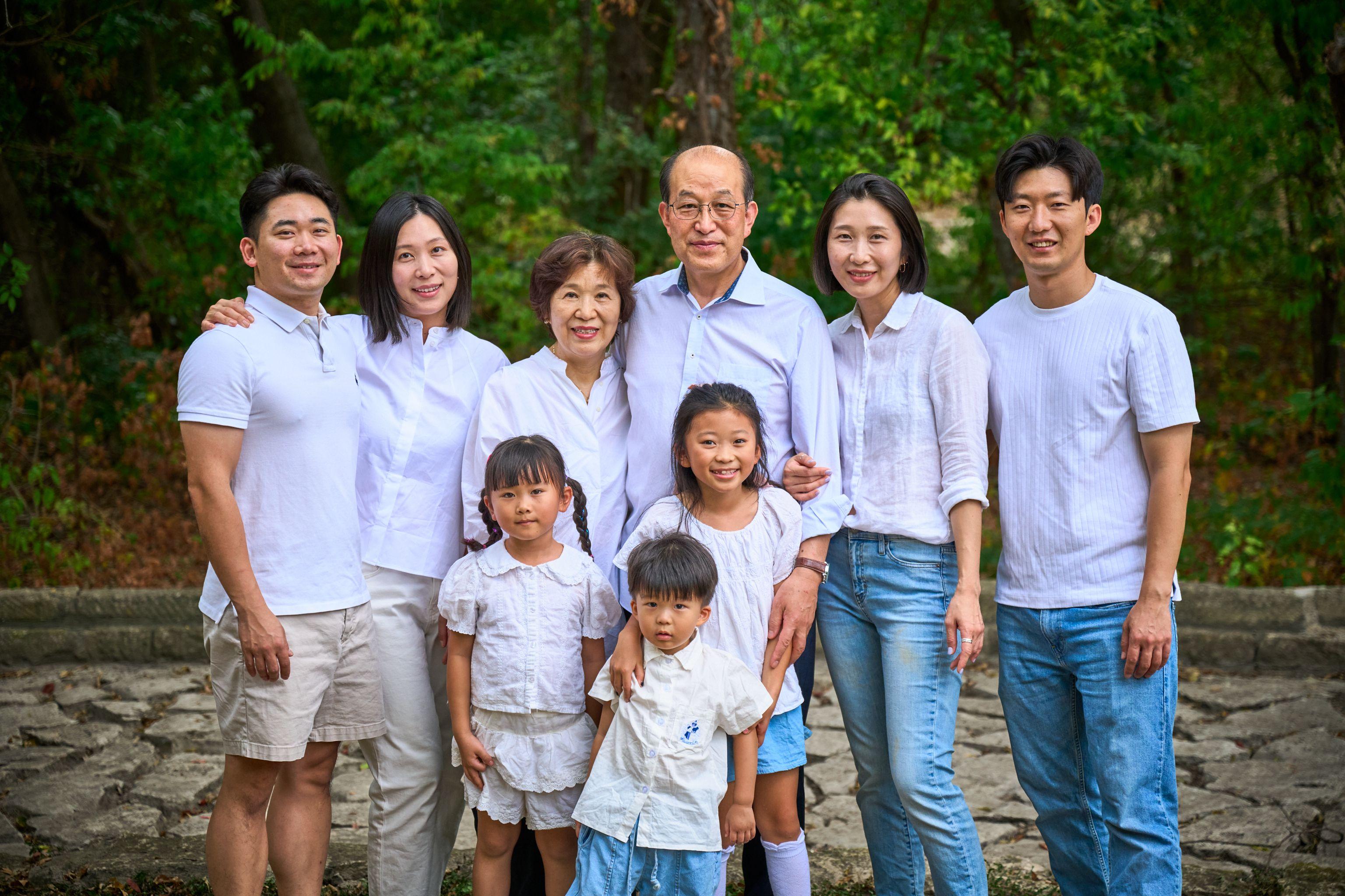 Large multi-generation family dressed in white standing together under the trees at Mills Pond — Mills Pond photography, Austin A large multi-generation family dressed in white standing together under the trees at Mills Pond