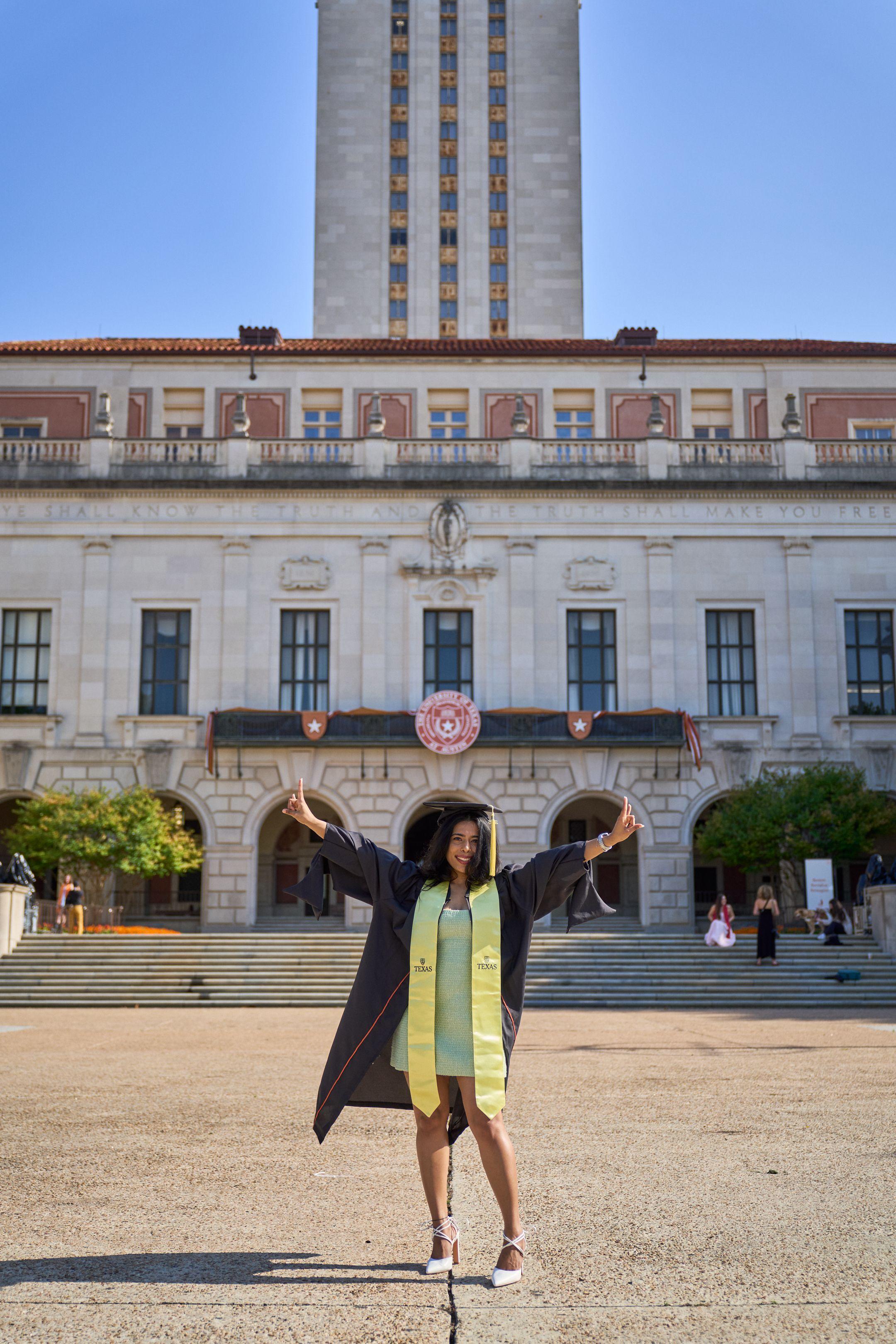 Graduate in cap and gown throwing her arms wide in front of a university building — Graduation & Prom photography, Austin A graduate in cap and gown throwing her arms wide in front of a university building.