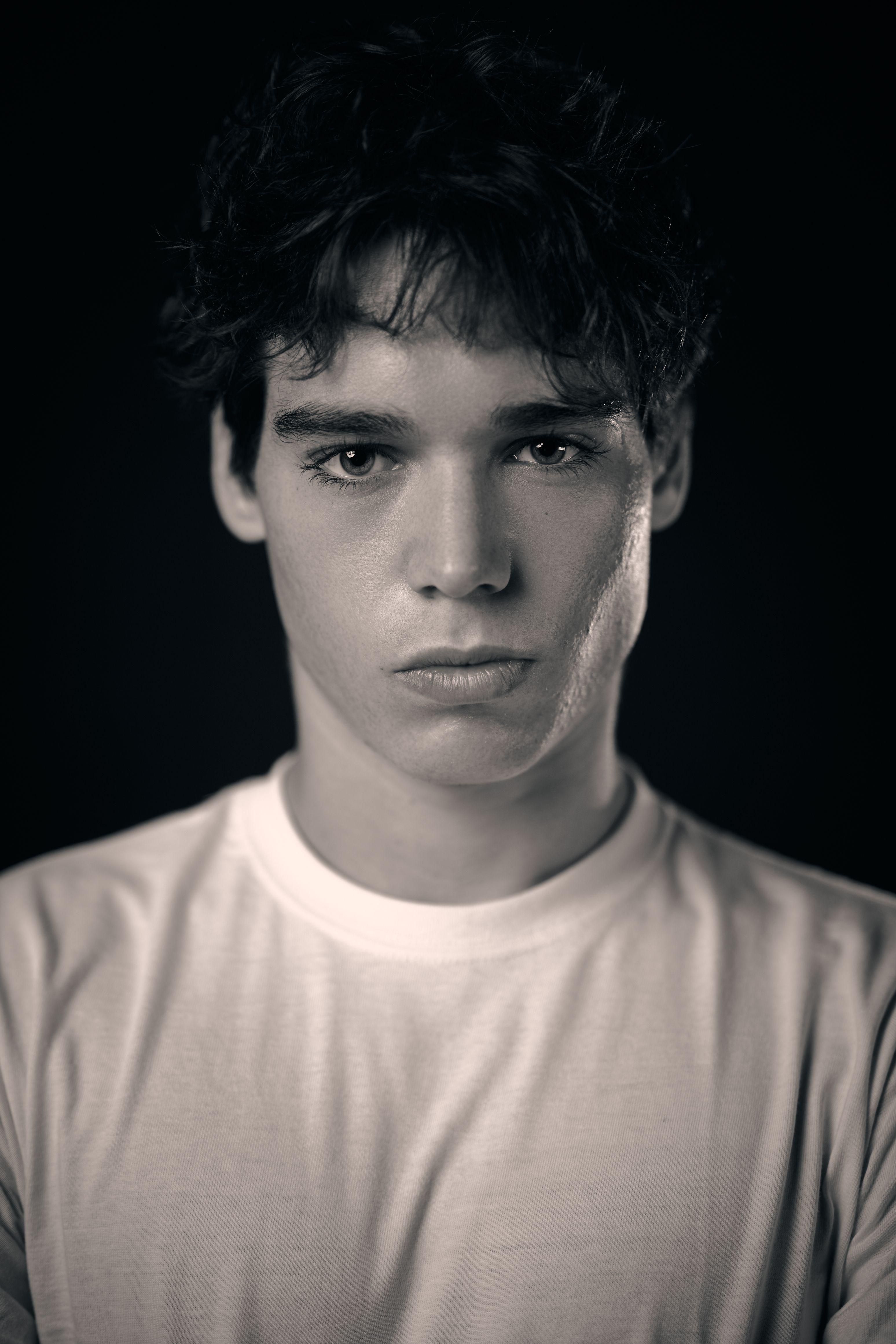 Young actor in a white t-shirt lit dramatically against a dark background — Headshot photography, Austin A young actor in a white t-shirt lit dramatically against a dark background.