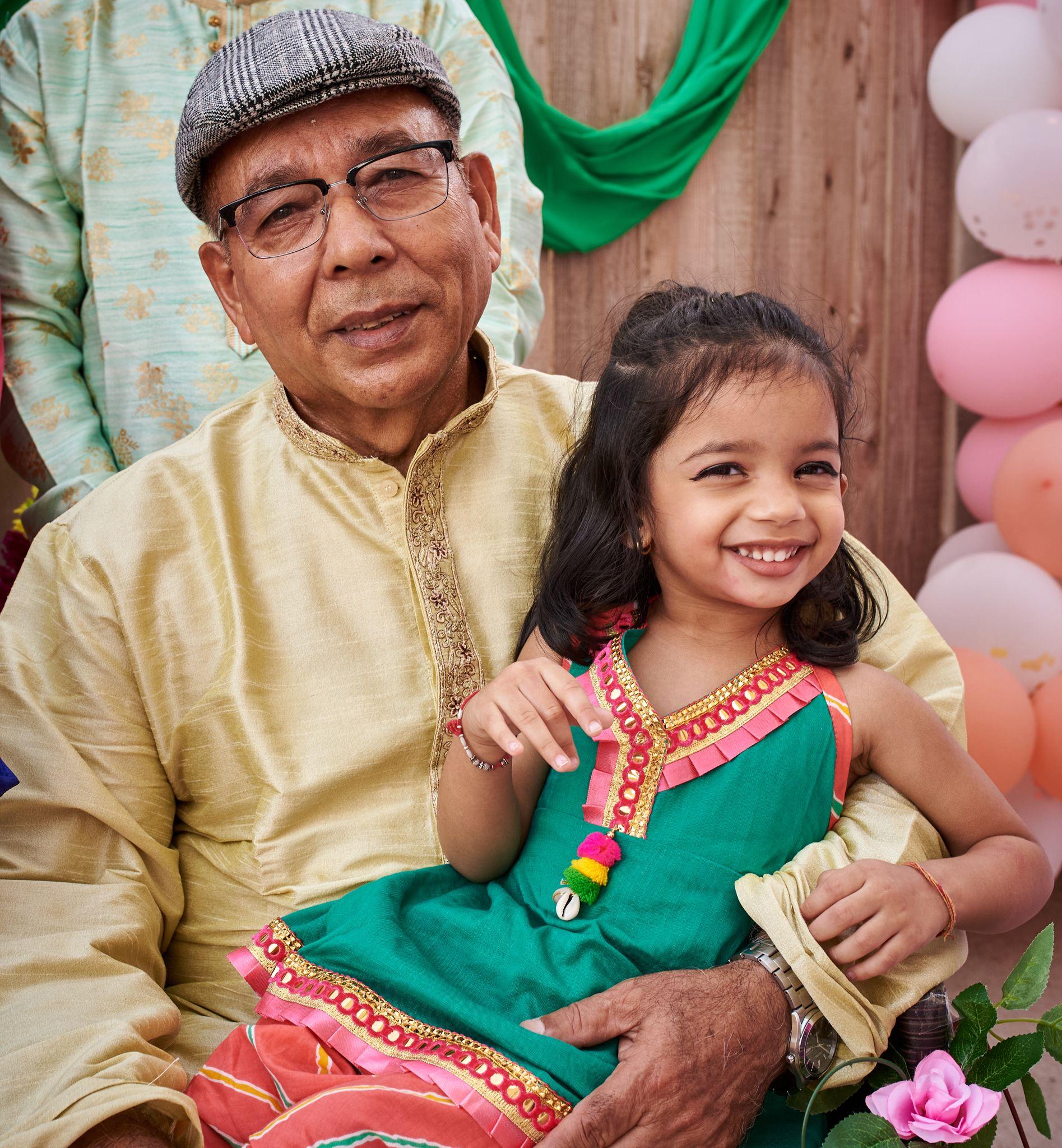 Grandfather in a gold kurta holding his granddaughter in a green and pink outfit — Family Parties photography, Austin A grandfather in a gold kurta holding his granddaughter in a green and pink outfit.