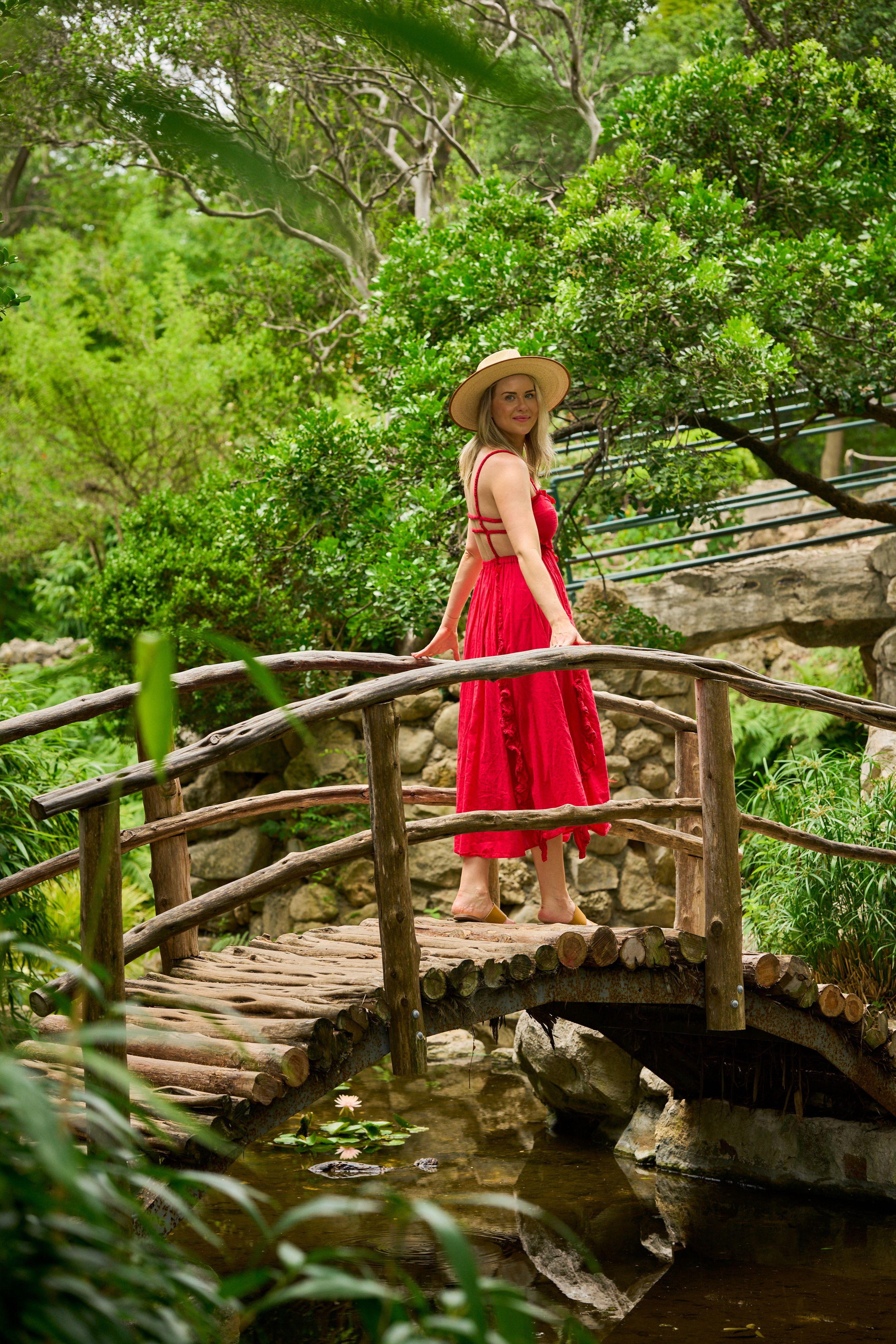 Woman in a long red dress standing on the arched wooden bridge over the pond — Zilker Botanical Gardens photography, Austin Zilker Botanical Gardens