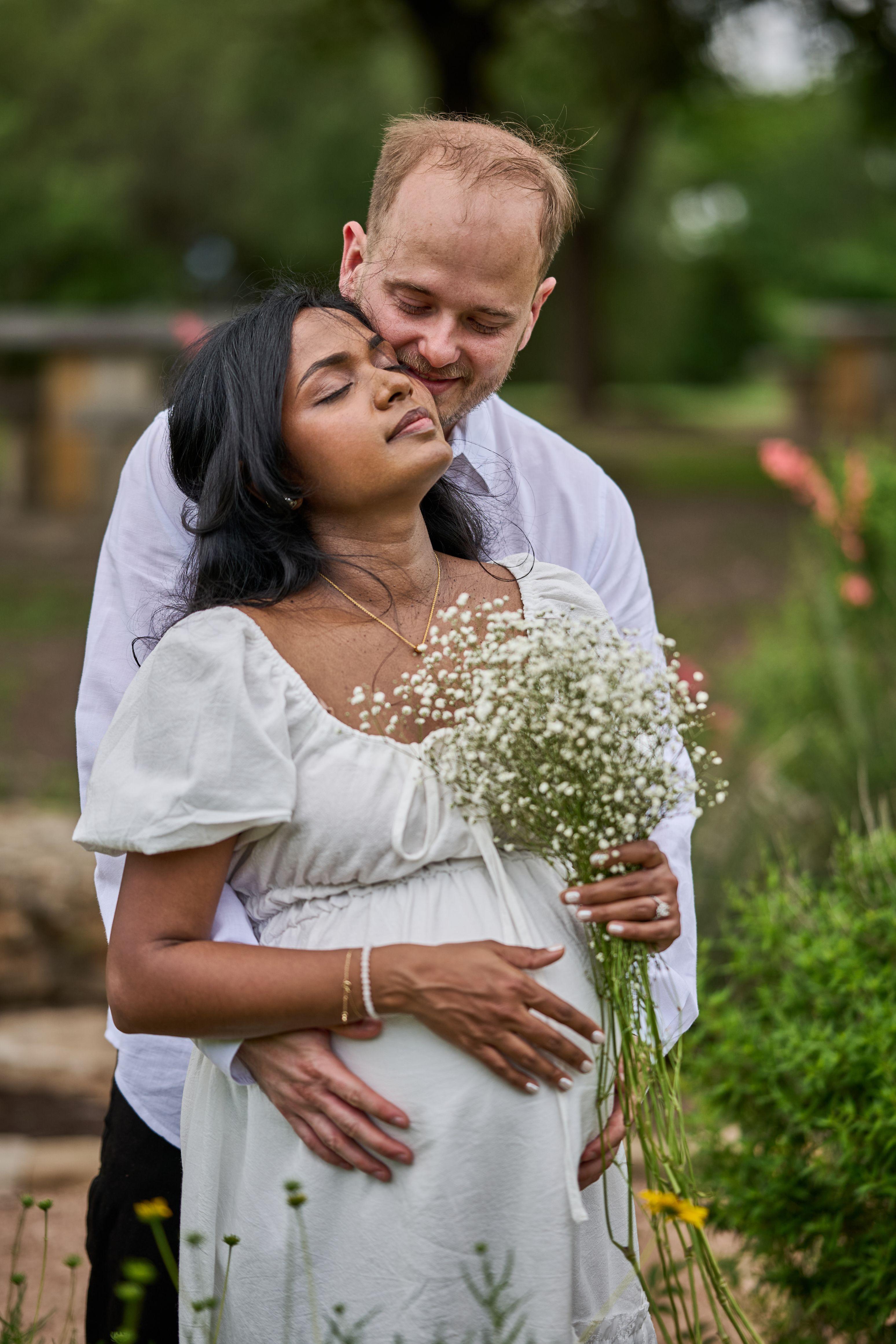 Man kissing an expectant mother's temple as she holds a bunch of baby's breath — Mueller Lake Park & Butterfly Garden photography, Austin A man kissing an expectant mother's temple as she holds a bunch of baby's breath