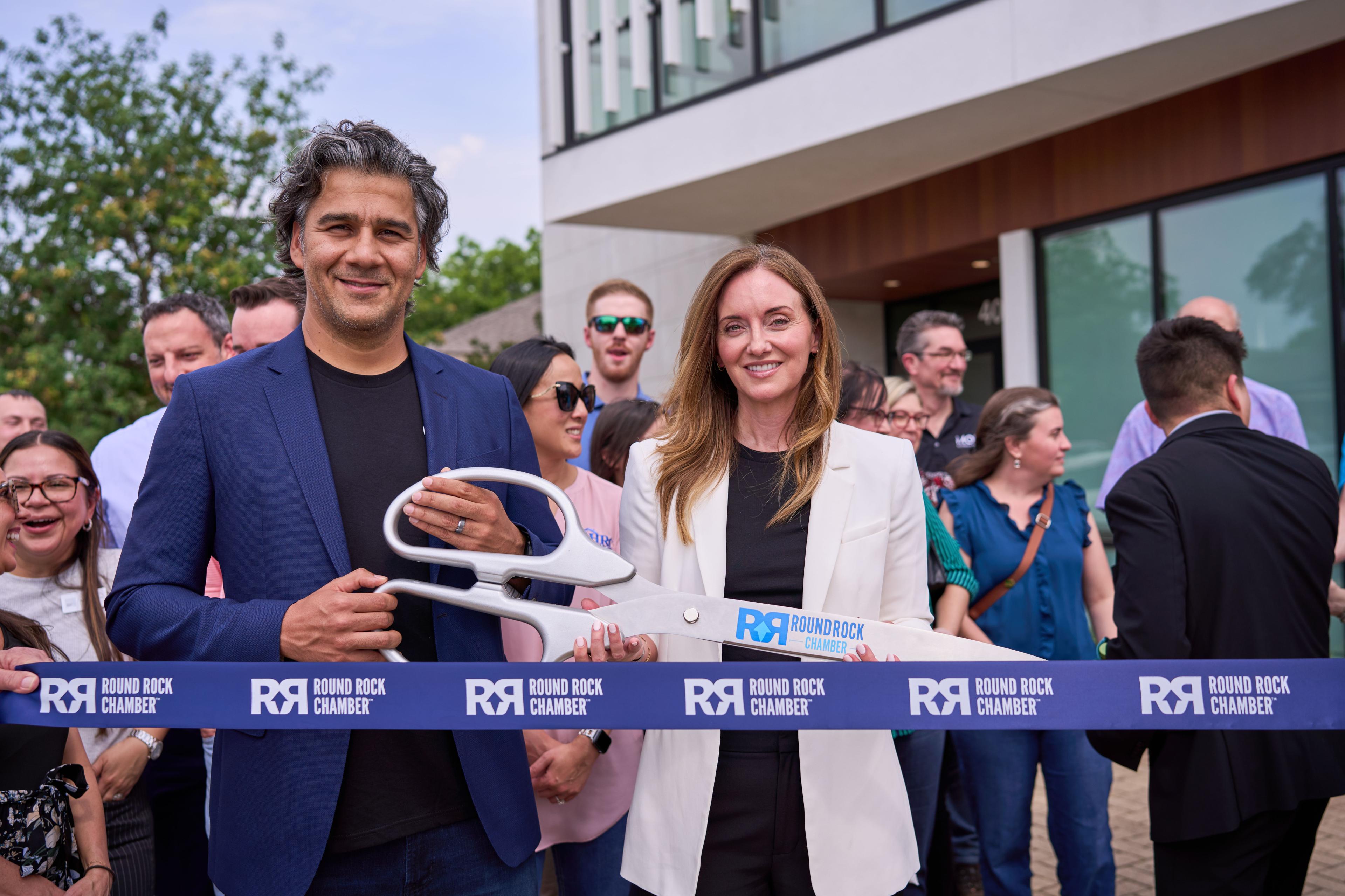 Ribbon-cutting at a Round Rock Chamber event with oversized ceremonial scissors — Brand activation photography, Austin A ribbon-cutting at a Round Rock Chamber event with oversized ceremonial scissors.
