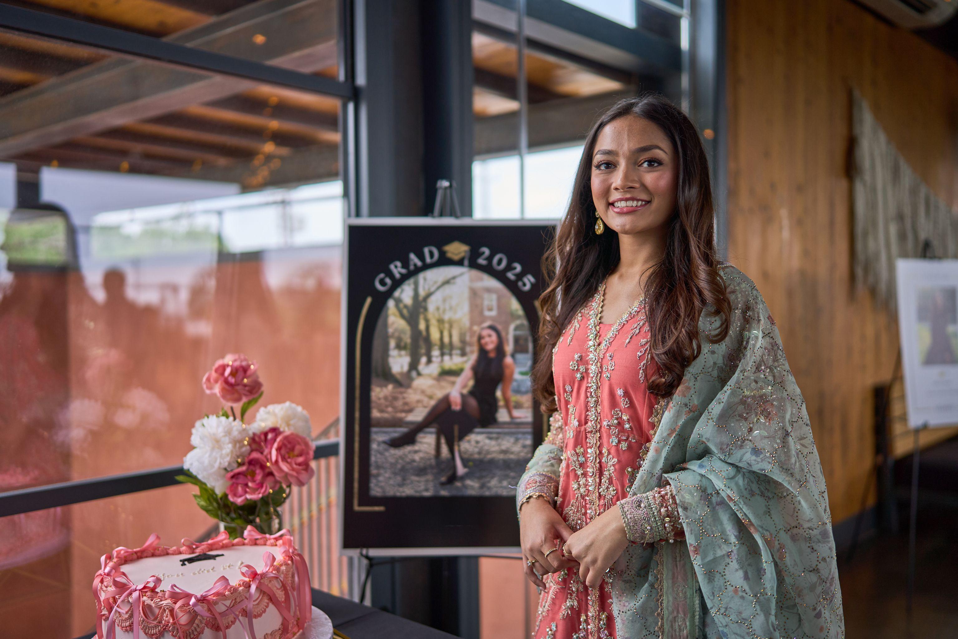 Graduate in a pink embroidered outfit beside her 'Grad 2025' photo board — Graduation & Prom photography, Austin A graduate in a pink embroidered outfit beside her 'Grad 2025' photo board.