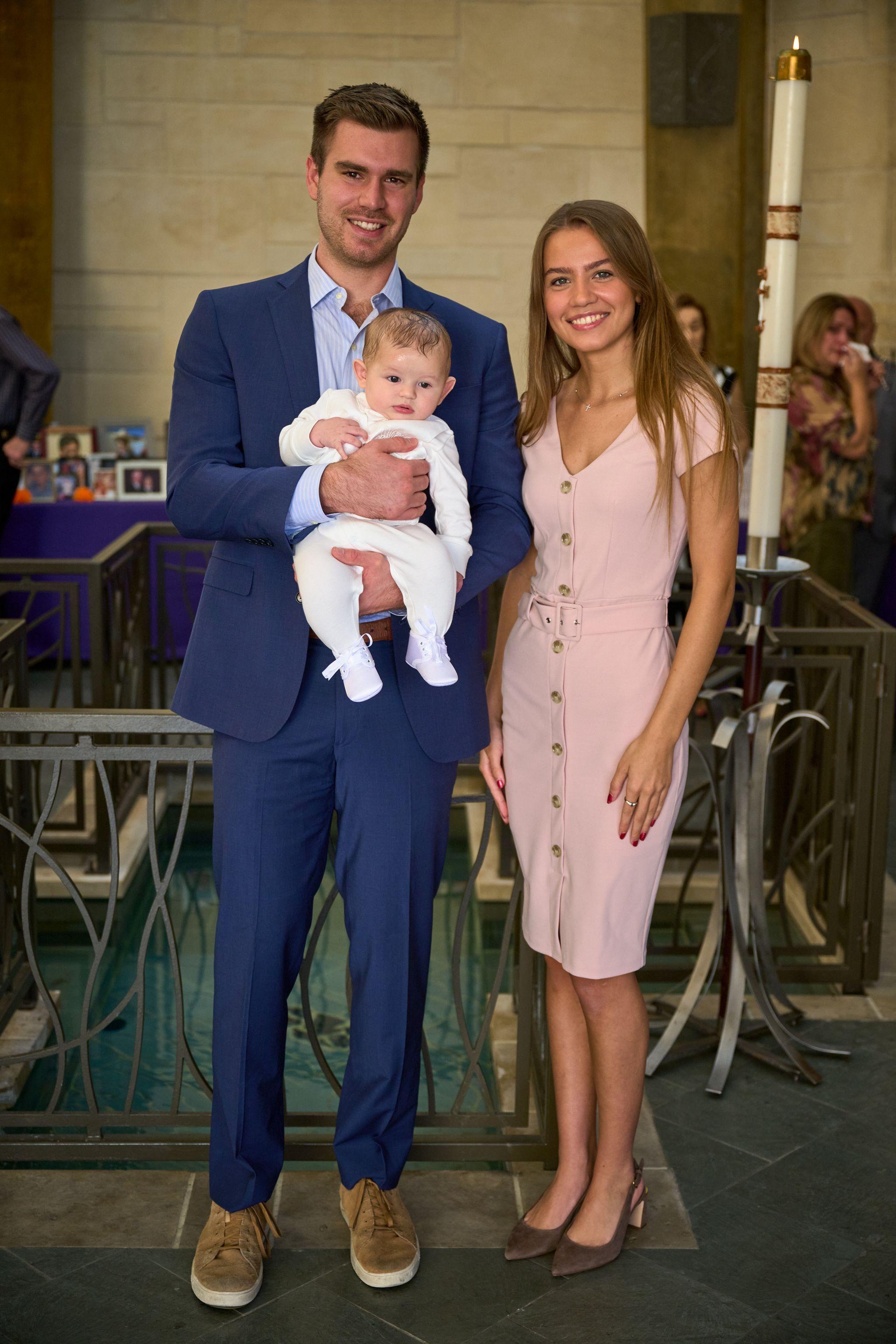 Parents standing together holding their baby in a christening gown inside a church — Religious Ceremonies photography, Austin Parents standing together holding their baby in a christening gown inside a church.