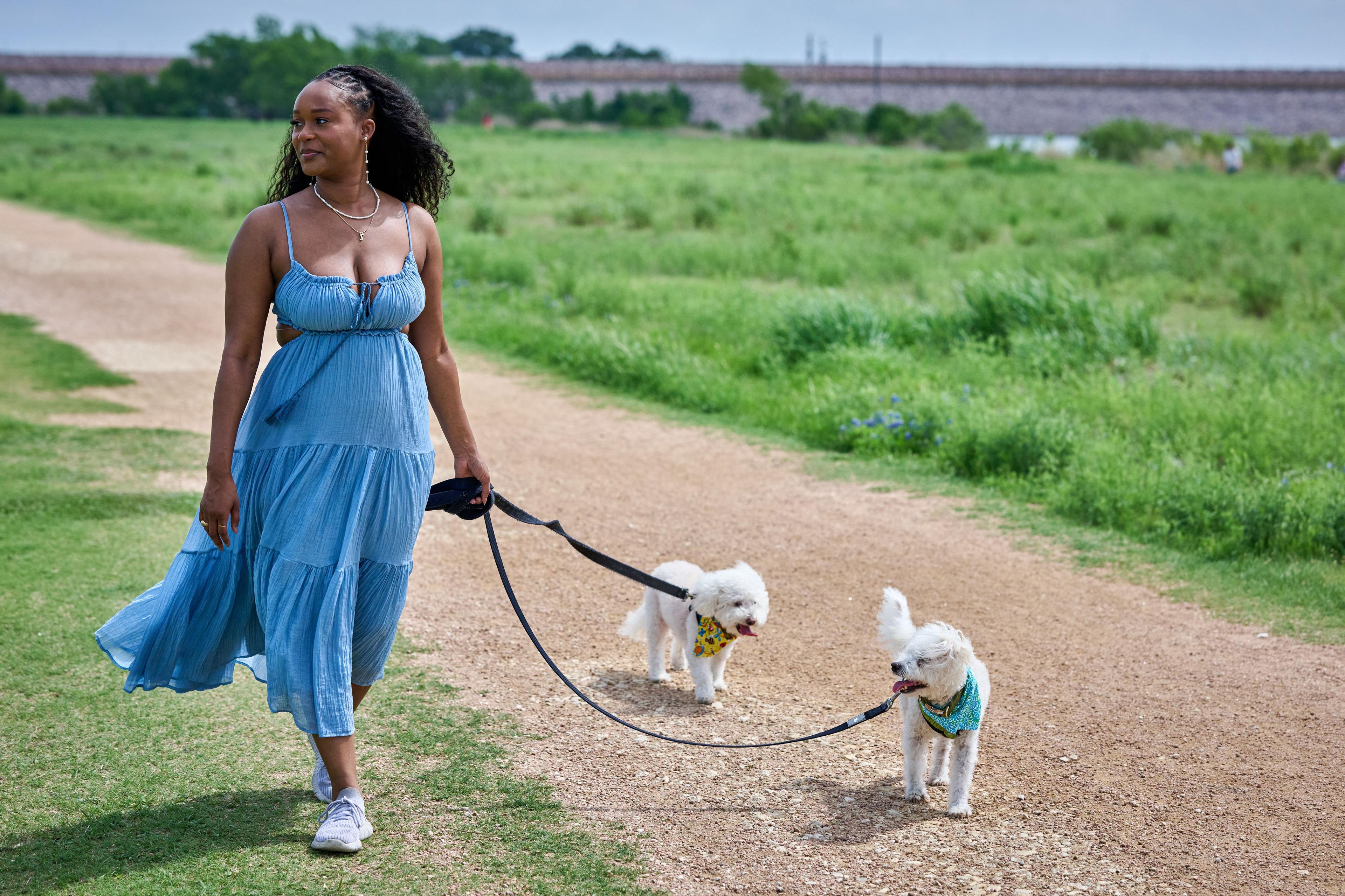Woman walking two small white dogs down the gravel trail through the meadow — Brushy Creek Lake Park photography, Austin A woman walking two small white dogs down the gravel trail through the meadow at Brushy Creek Lake Park