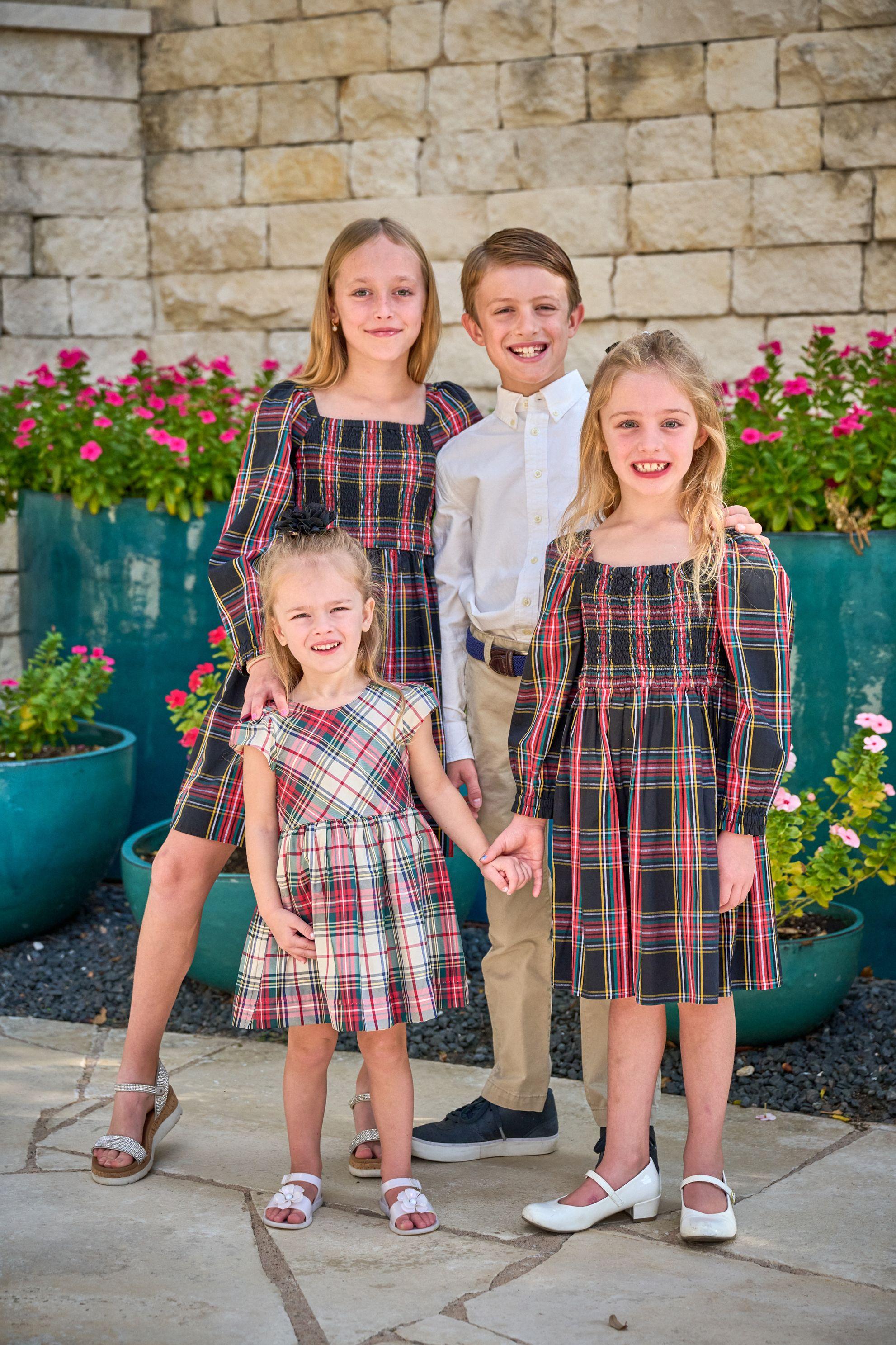 Four children in tartan standing hand in hand in front of a stone wall — Kids Portraits photography, Austin Four children in tartan standing hand in hand in front of a stone wall.