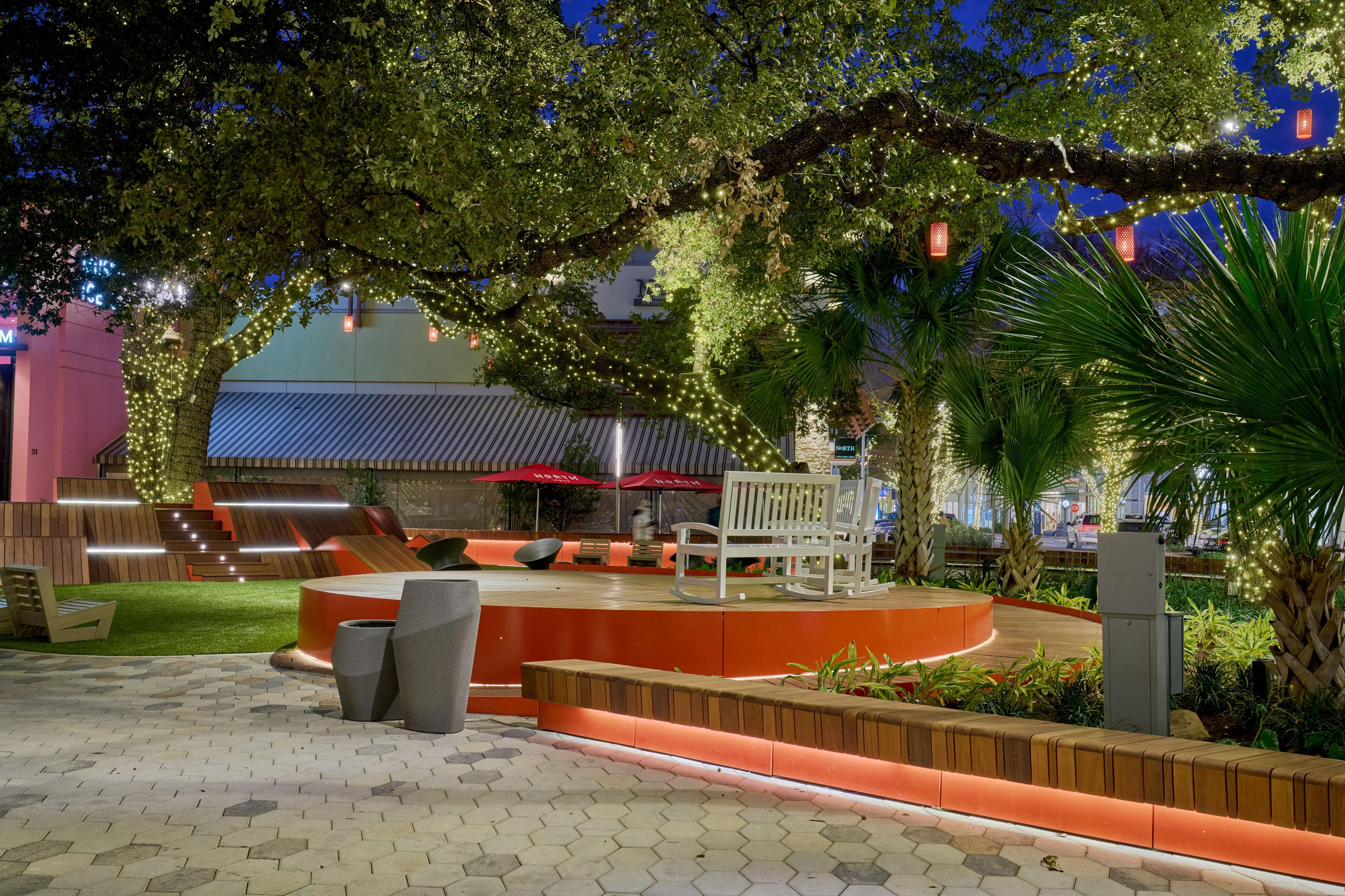 Outdoor amenity courtyard strung with lights beneath large oak trees — Architectural photography, Austin An outdoor amenity courtyard strung with lights beneath large oak trees.