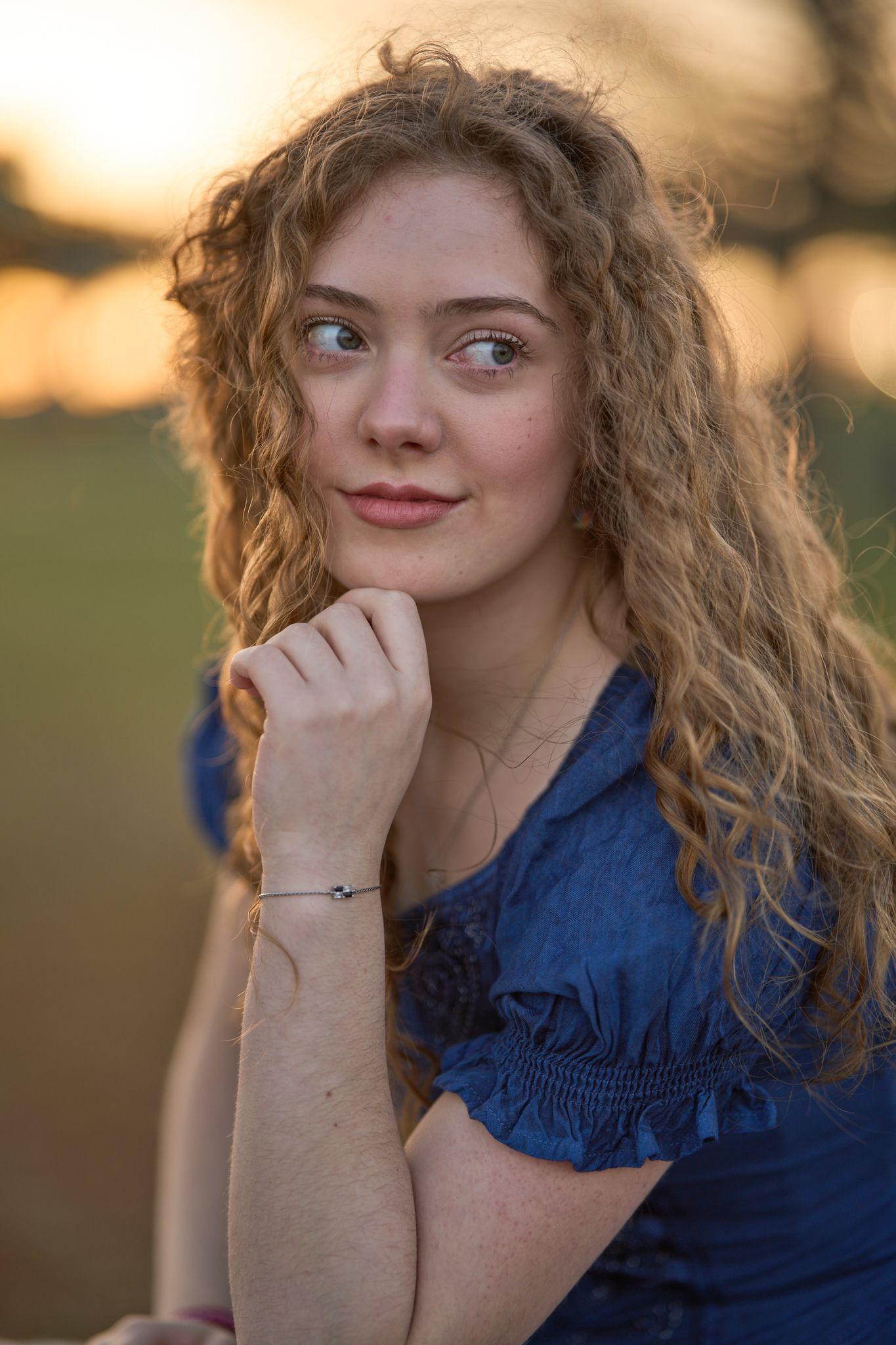 Young woman in blue with her hand raised to her chin, backlit by the last of the sun — Round Rock Old Settlers Park photography, Austin A young woman in blue with her hand raised to her chin, backlit by the last of the sun at Old Settlers Park