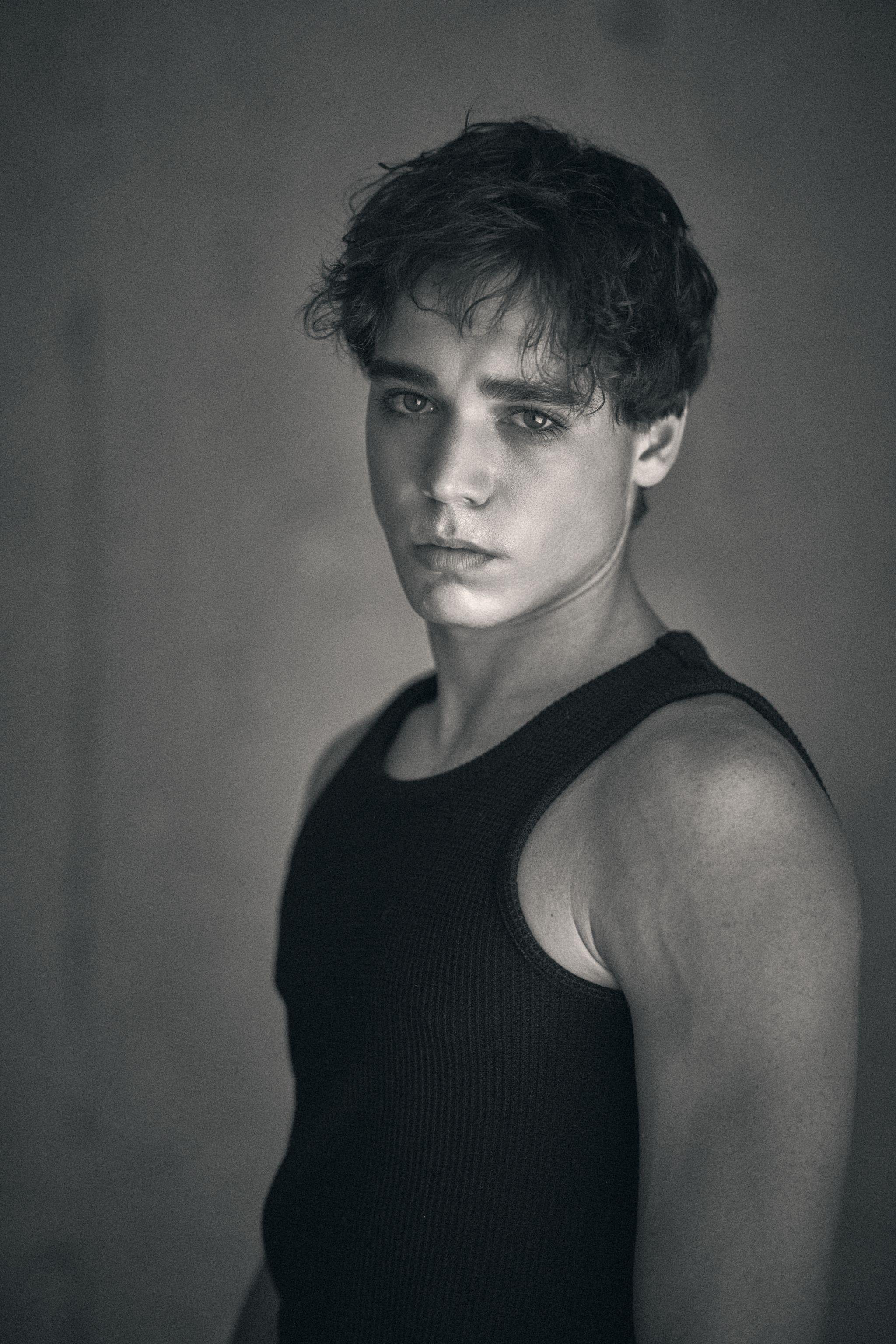 Black and white portrait of a young male model in a black ribbed tank top — E-commerce & apparel photography, Austin Black and white portrait of a young male model in a black ribbed tank top against a concrete wall