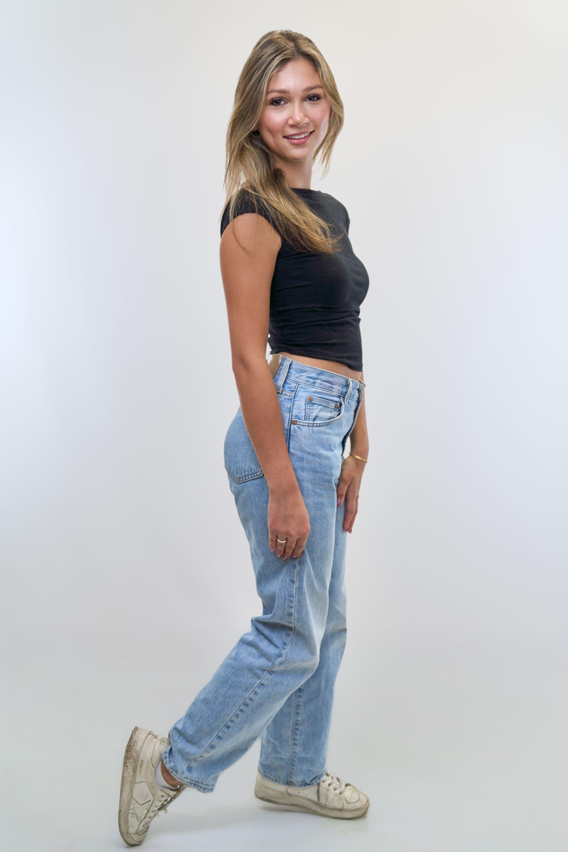 Side-on full-length studio digital of a model in a black top and jeans — Fashion & editorial photography, Austin A side-on full-length studio digital of a model in a black top and jeans.