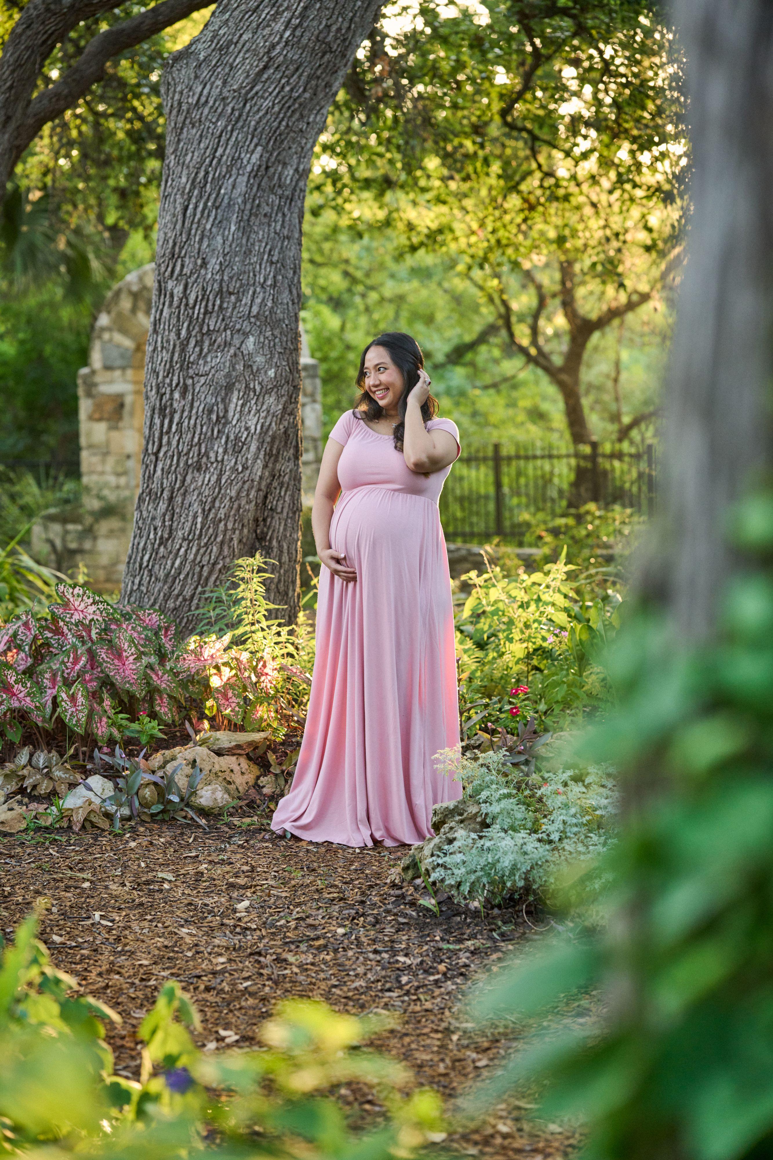 Expectant mother in a long pink dress standing under a live oak at Mayfield Park — Mayfield Park photography, Austin An expectant mother in a long pink dress standing under a live oak at Mayfield Park