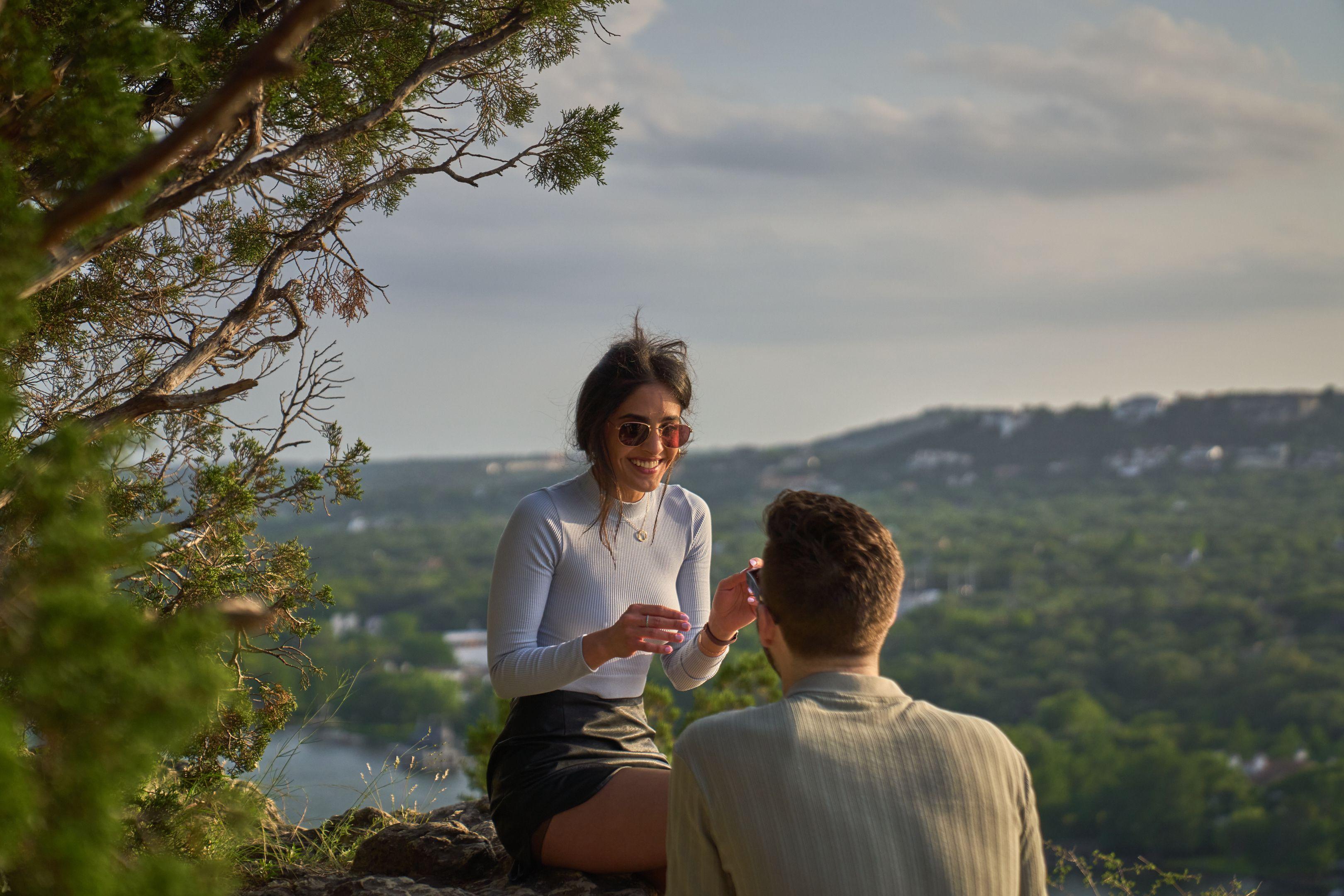 Couple sitting together on the rocks at Mount Bonnell at golden hour, the Hill Country — Engagement & Proposals photography, Austin A couple sitting together on the rocks at Mount Bonnell at golden hour, the Hill Country and Lake Austin behind them.