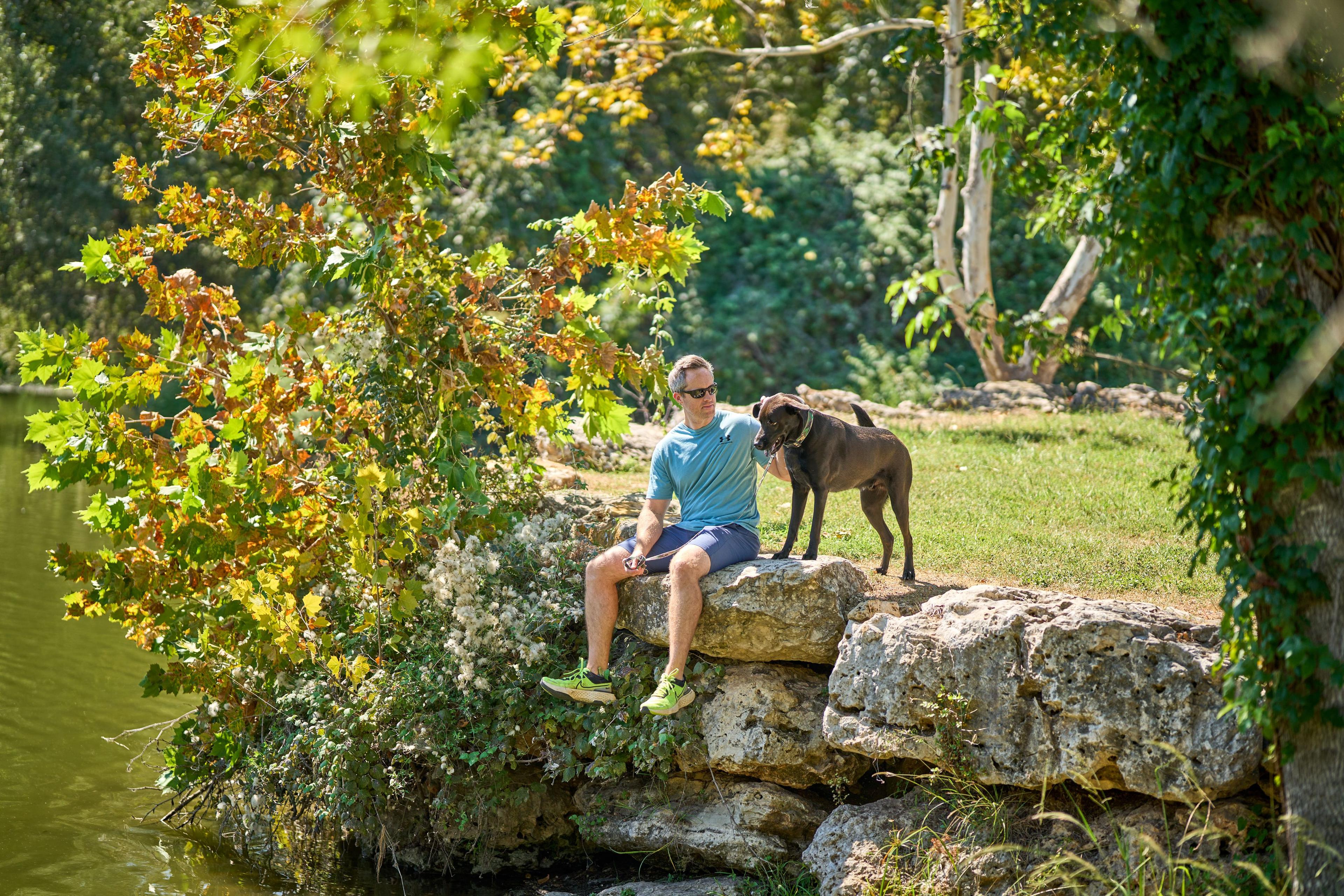 Man sitting on a limestone outcrop with his dog beside him — Olson Meadows Park photography, Austin A man sitting on a limestone outcrop with his dog beside him.