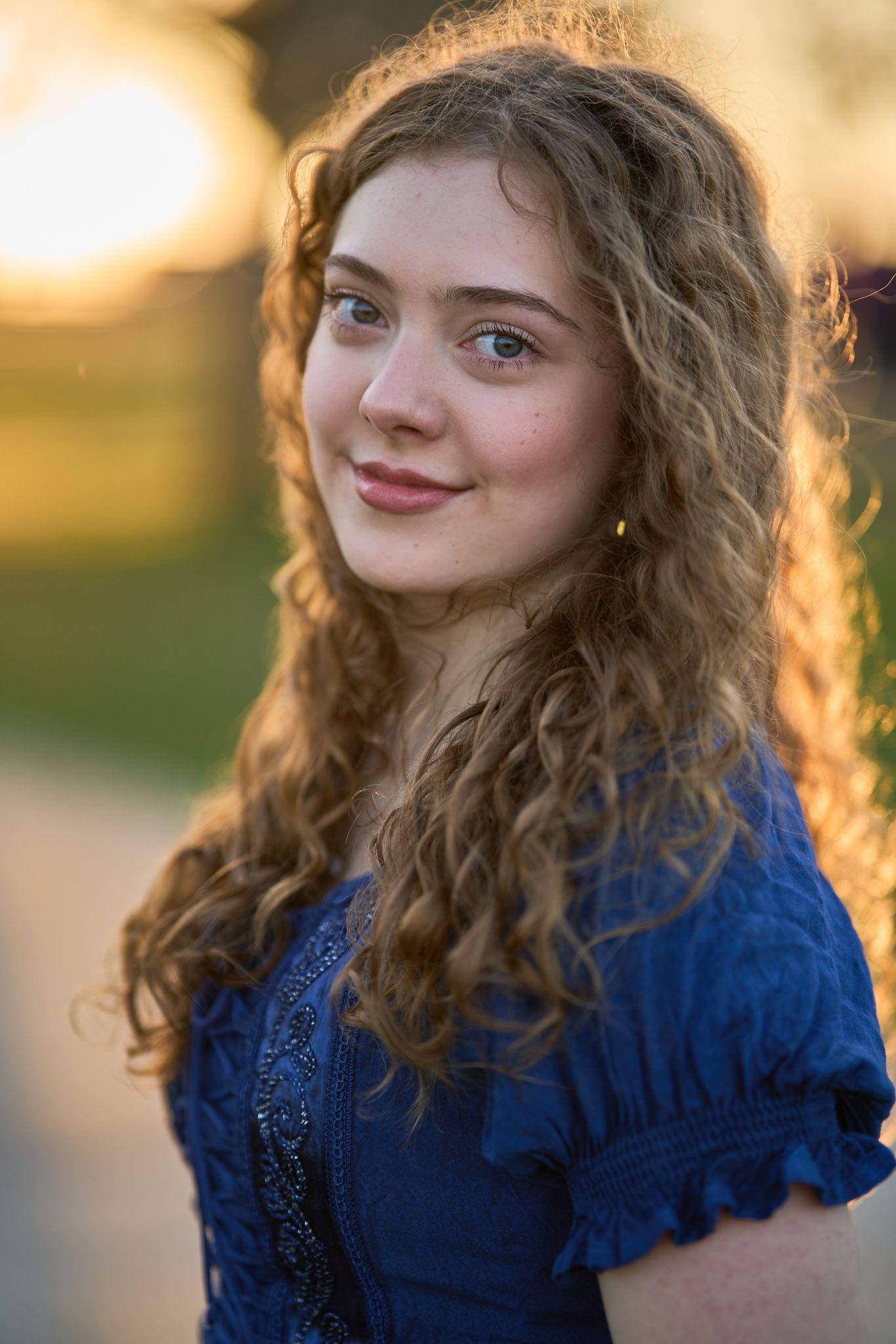 Young woman with curly hair in a blue top looking back over her shoulder, backlit — Round Rock Old Settlers Park photography, Austin A young woman with curly hair in a blue top looking back over her shoulder, backlit at Old Settlers Park
