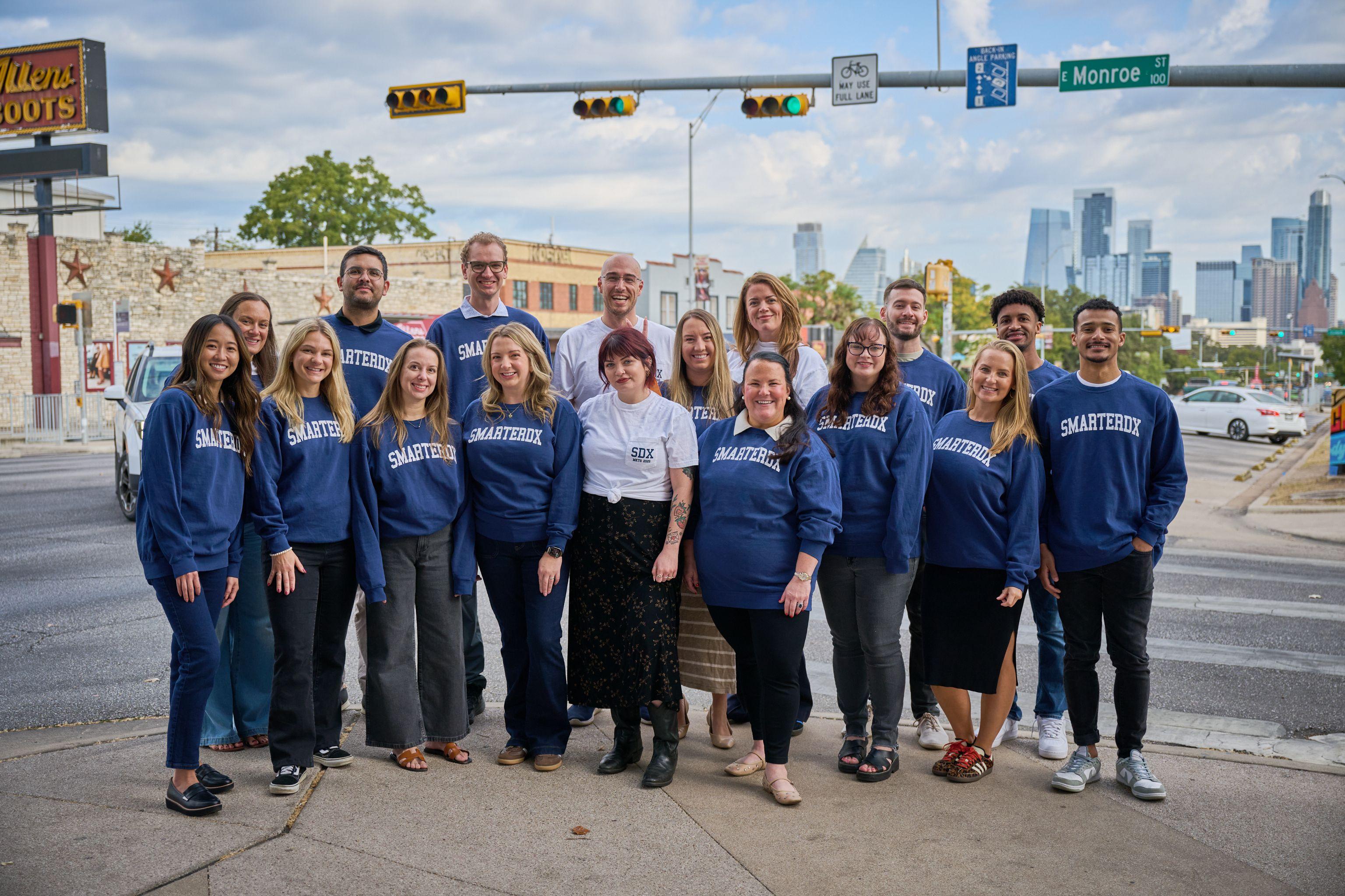 Team in matching blue sweatshirts posed together on a street with a traffic light overhead — South Congress (SoCo) photography, Austin A team in matching blue sweatshirts posed together on a street with a traffic light overhead