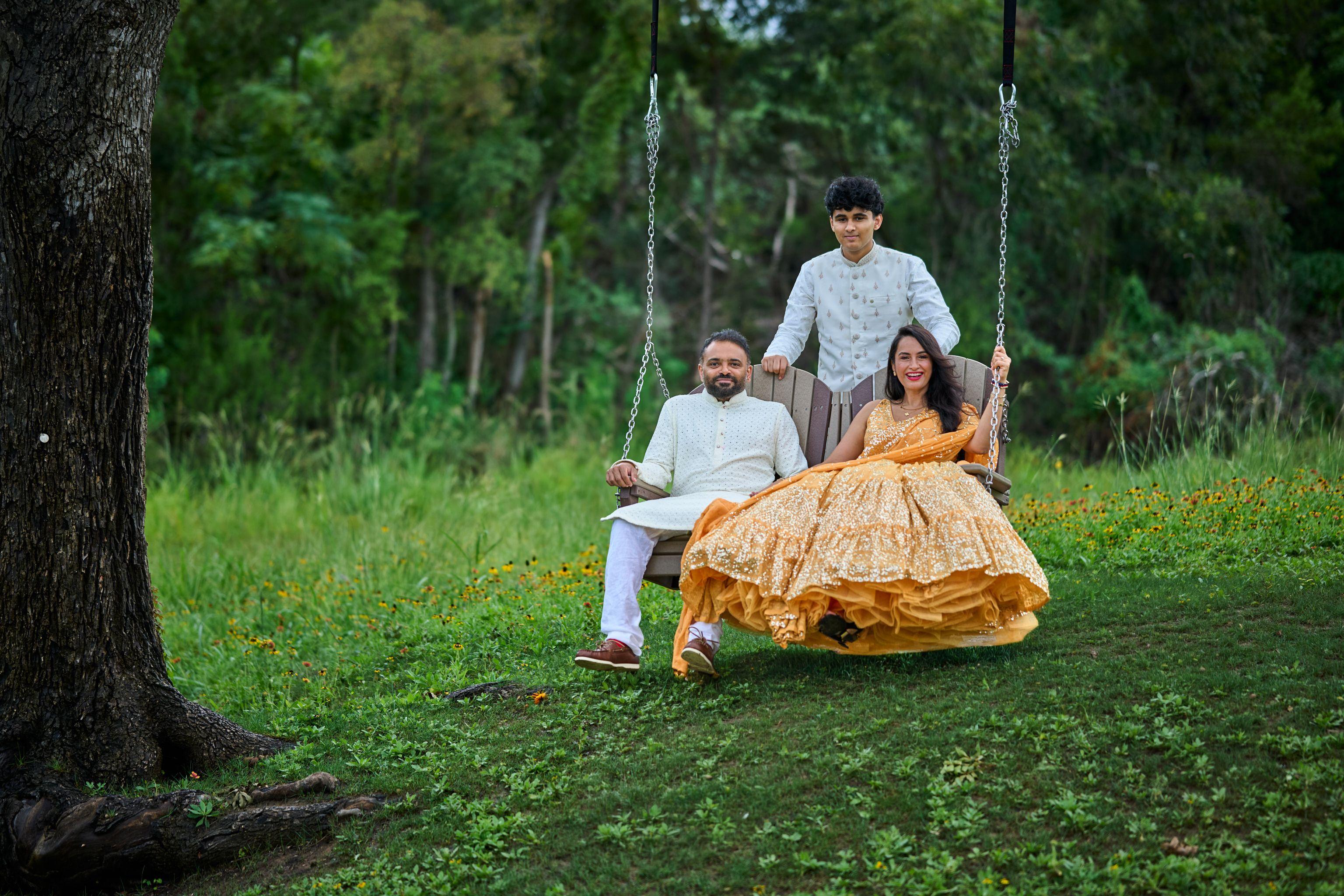 Family on the tree swing on the Cedar Park Public Library grounds, the woman — Cedar Park Public Library photography, Austin A family on the tree swing on the Cedar Park Public Library grounds, the woman in a gold lehenga seated and a teenager standing behind