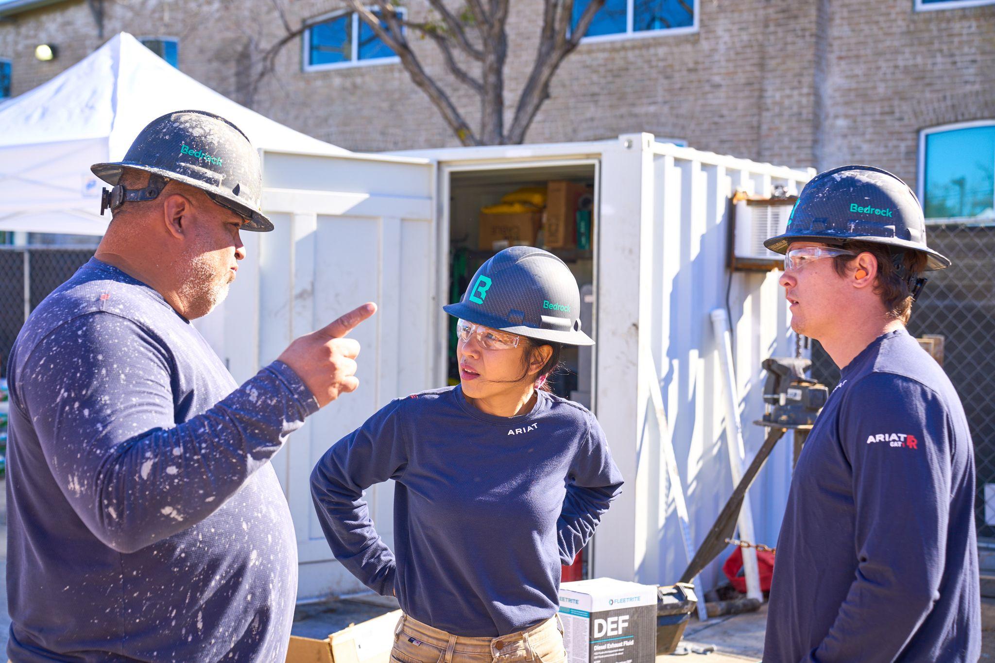Worker in a hard hat and safety glasses pointing while directing work — Industrial photography, Austin Worker in a hard hat and safety glasses pointing while directing work beside a white shipping container